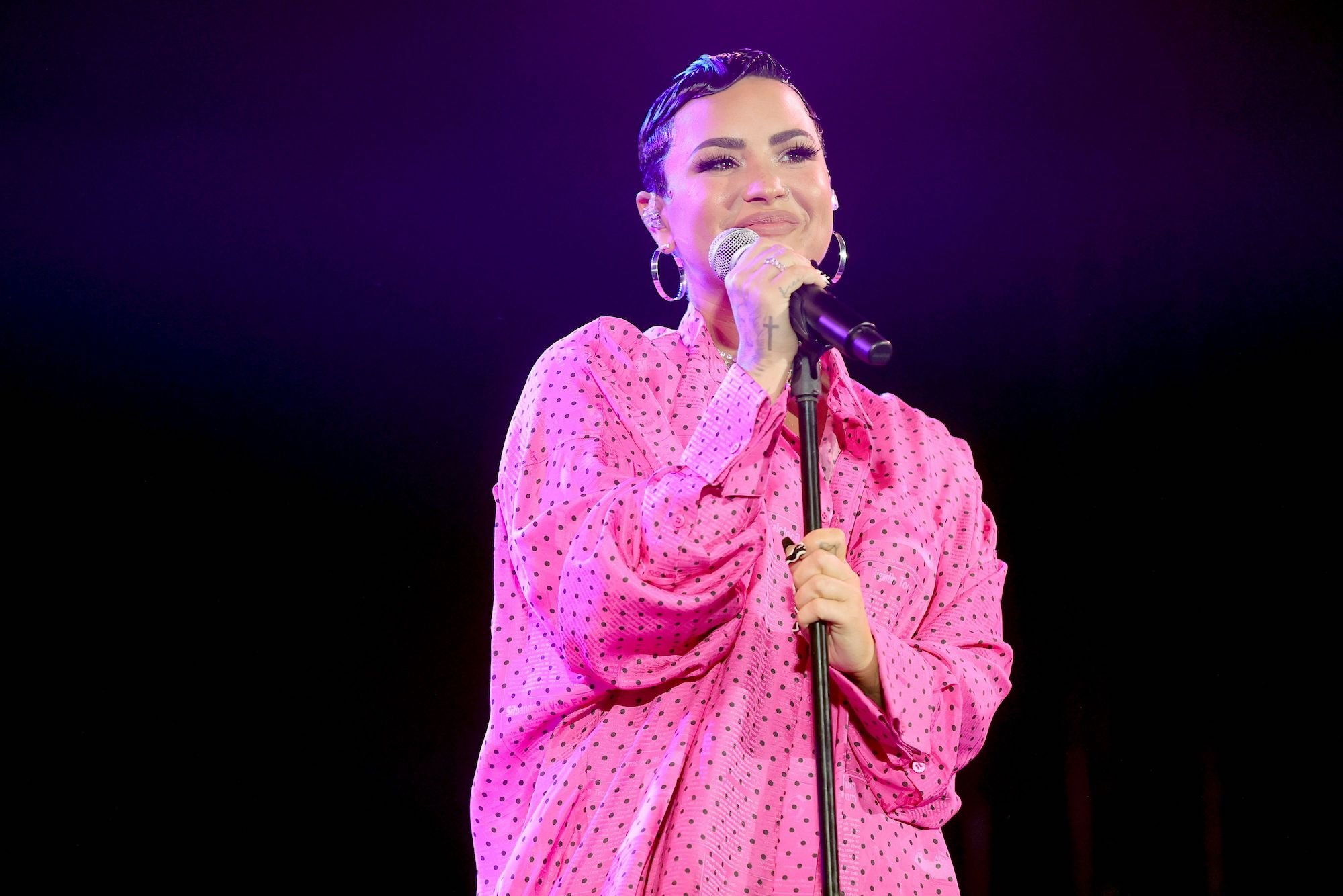 Demi Lovato in a pink shirt onstage