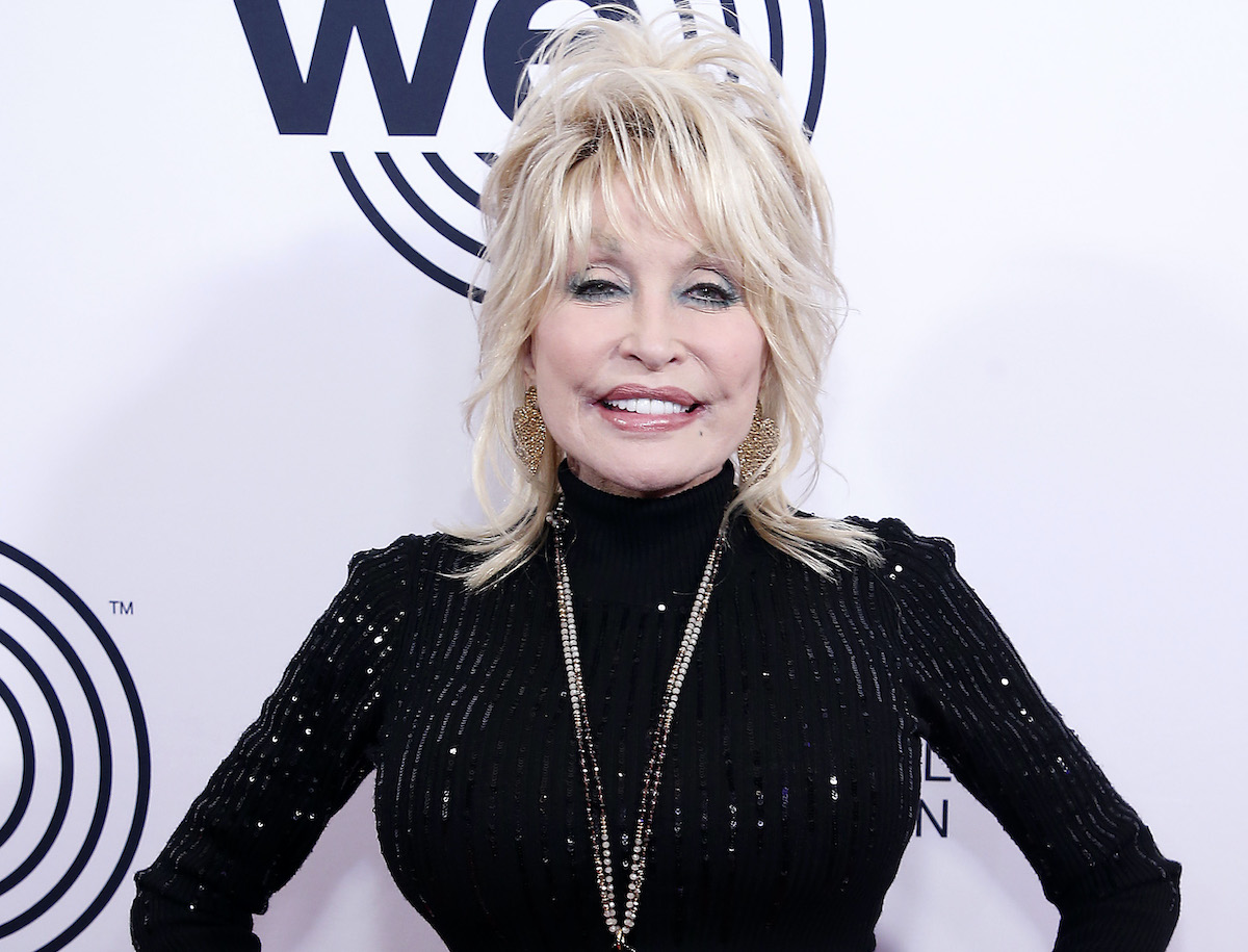 Dolly Parton wearing a black top smiling while on a red carpet | John Lamparski/Getty Images