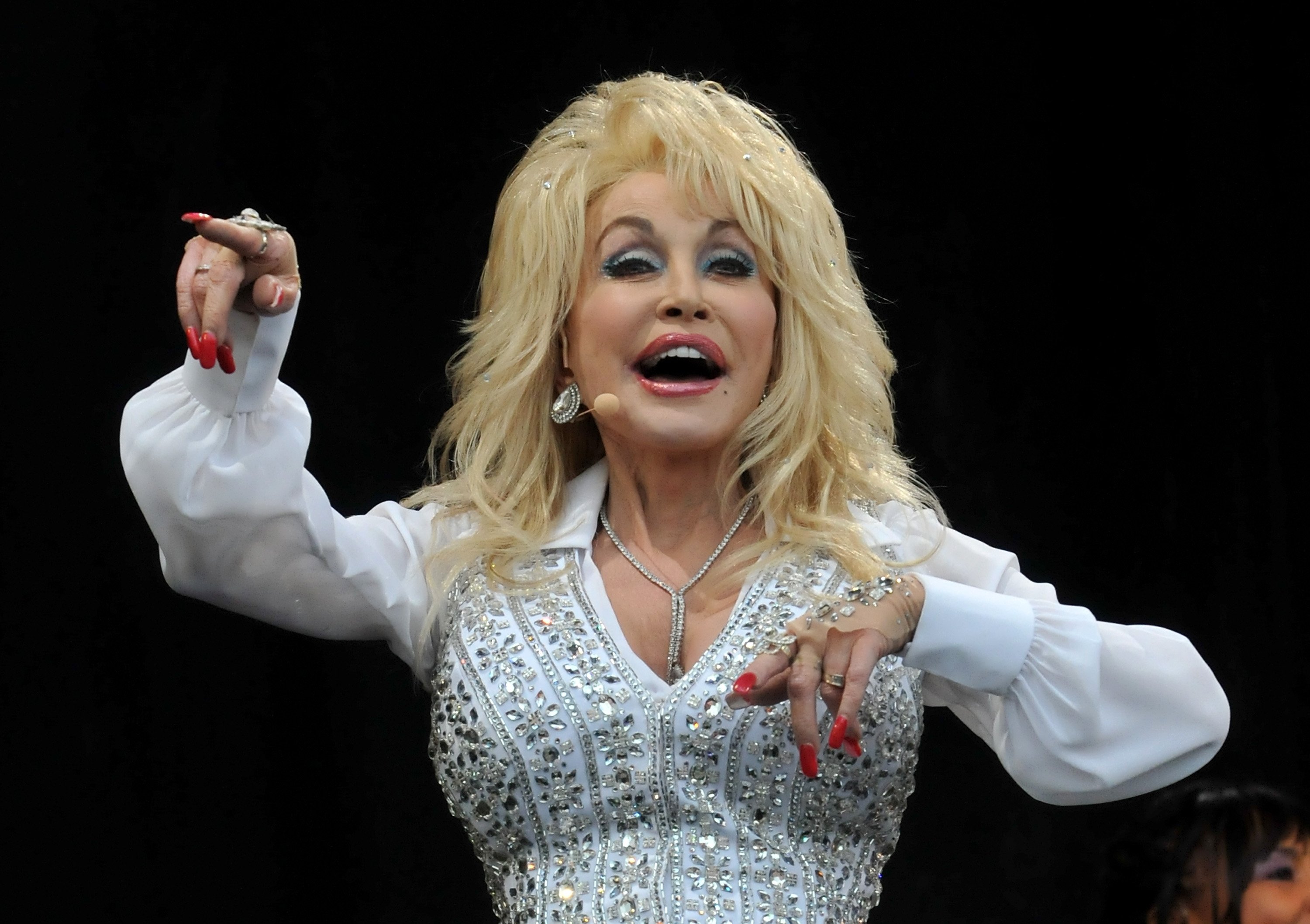 Dolly Parton performs on the Pyramid stage during day three of the Glastonbury Festival. She's singing and in an all-white outfit.