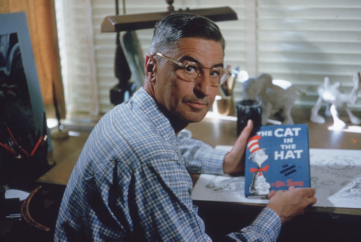 Photo of Theodor Seuss Geisel holding a copy of The Cat in the Hat 