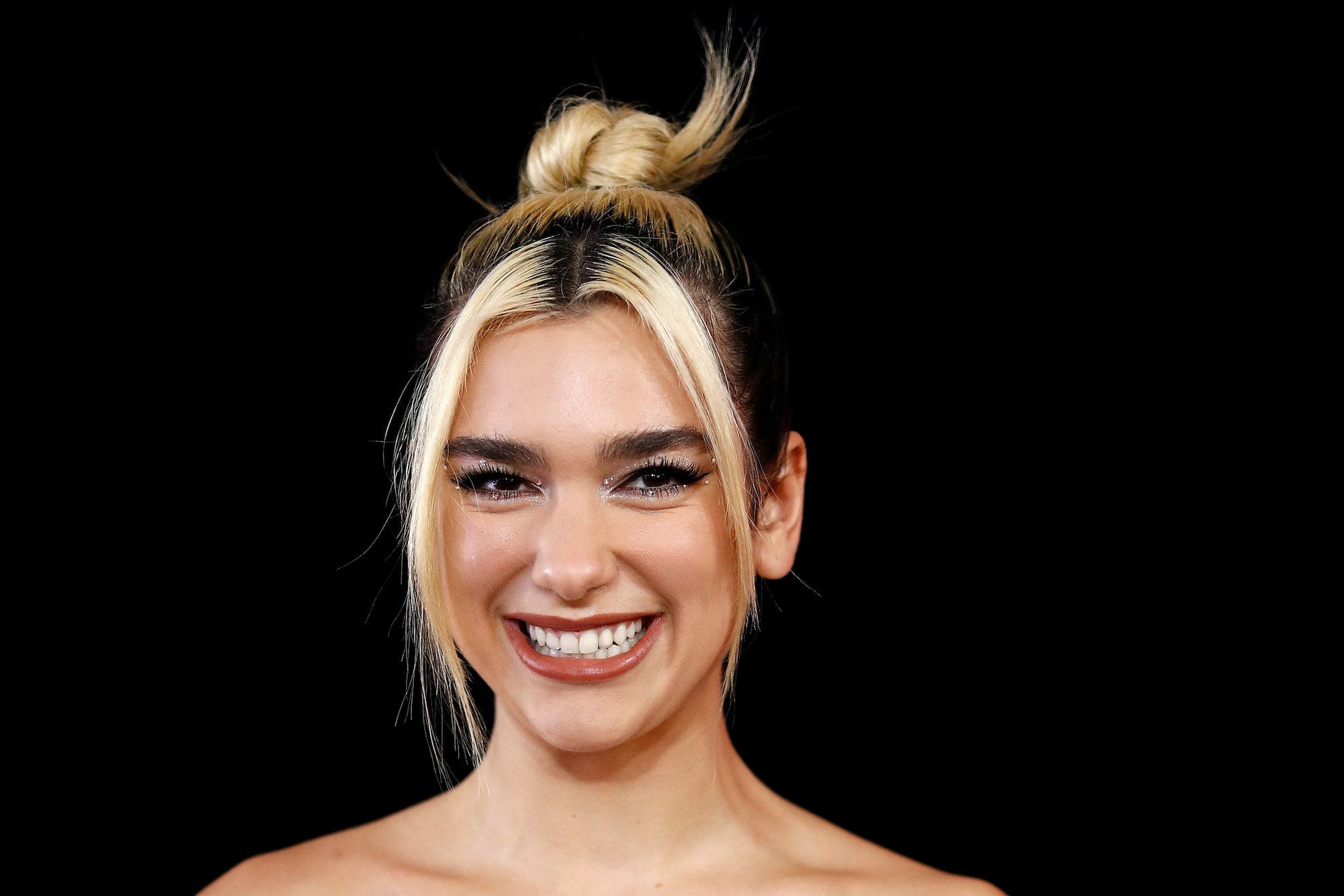 Dua Lipa smiling in front of a black ground
