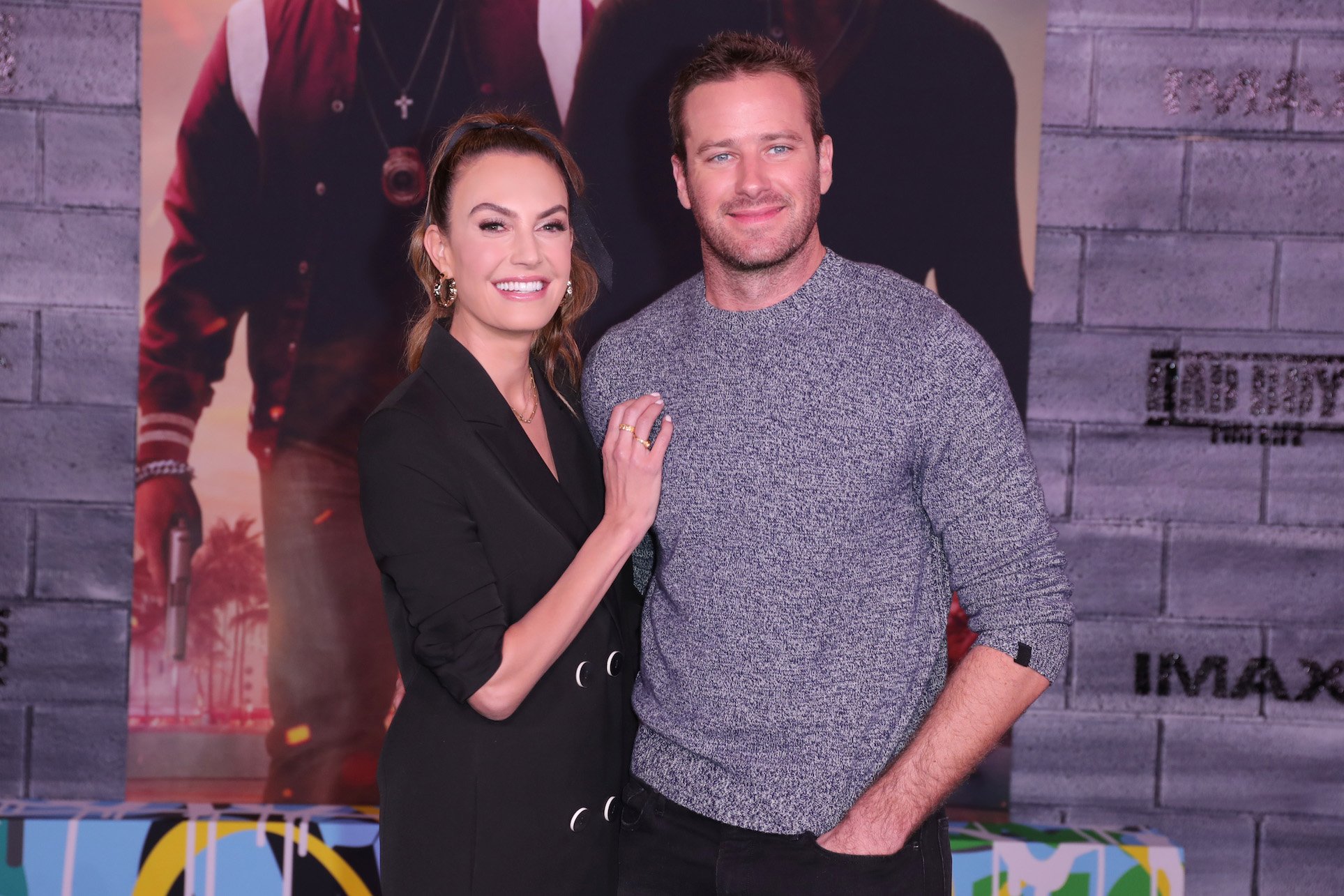 Elizabeth Chambers and Armie Hammer smiling for the camera. Armie Hammer's age is 33, and Elizabeth Chambers is 37