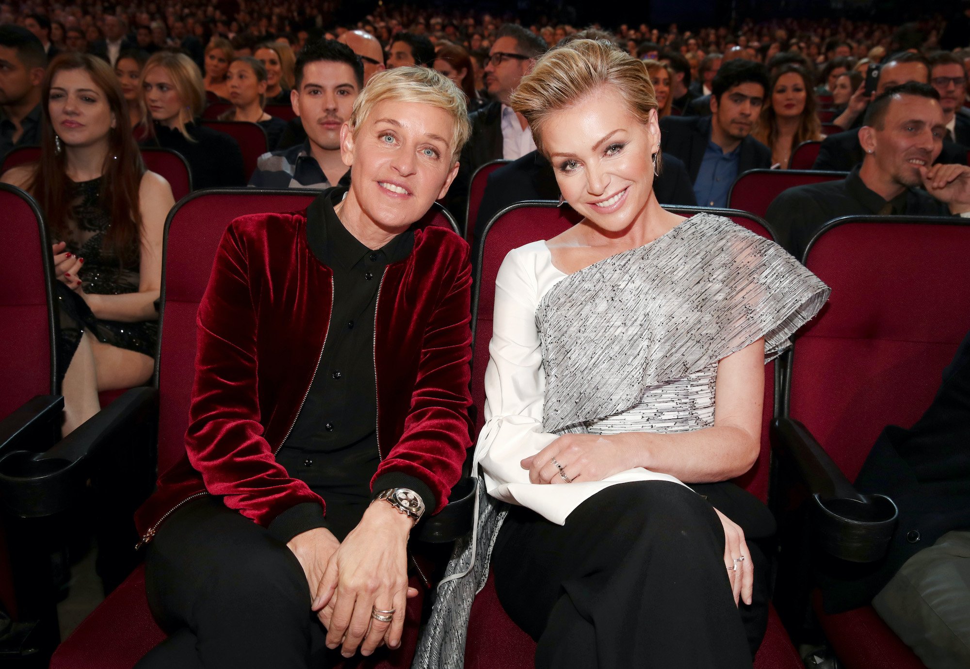 (L-R) Ellen DeGeneres and Portia de Rossi smiling, sitting in a theater