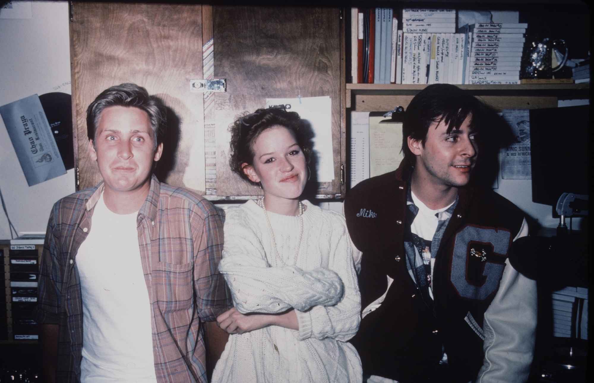 Actors Emilio Estevez, Molly Ringwald, and Judd Nelson smile in a candid photo together