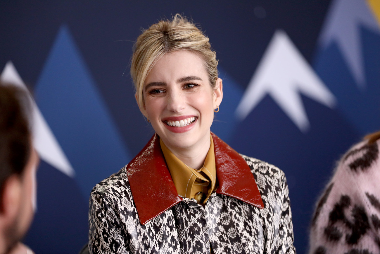 Emma Roberts smiling in front of blue background