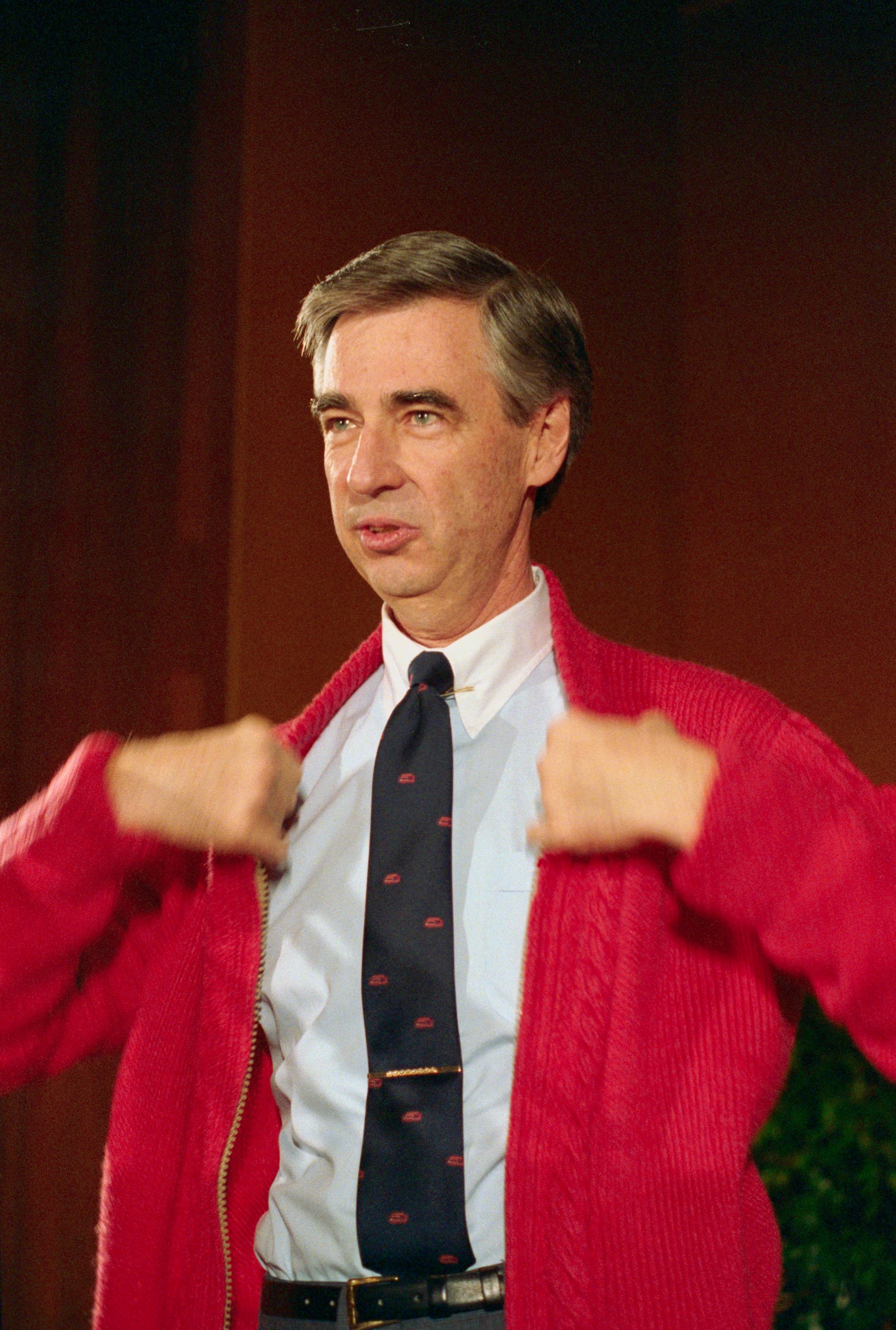 Fred Rogers putting on a red sweater