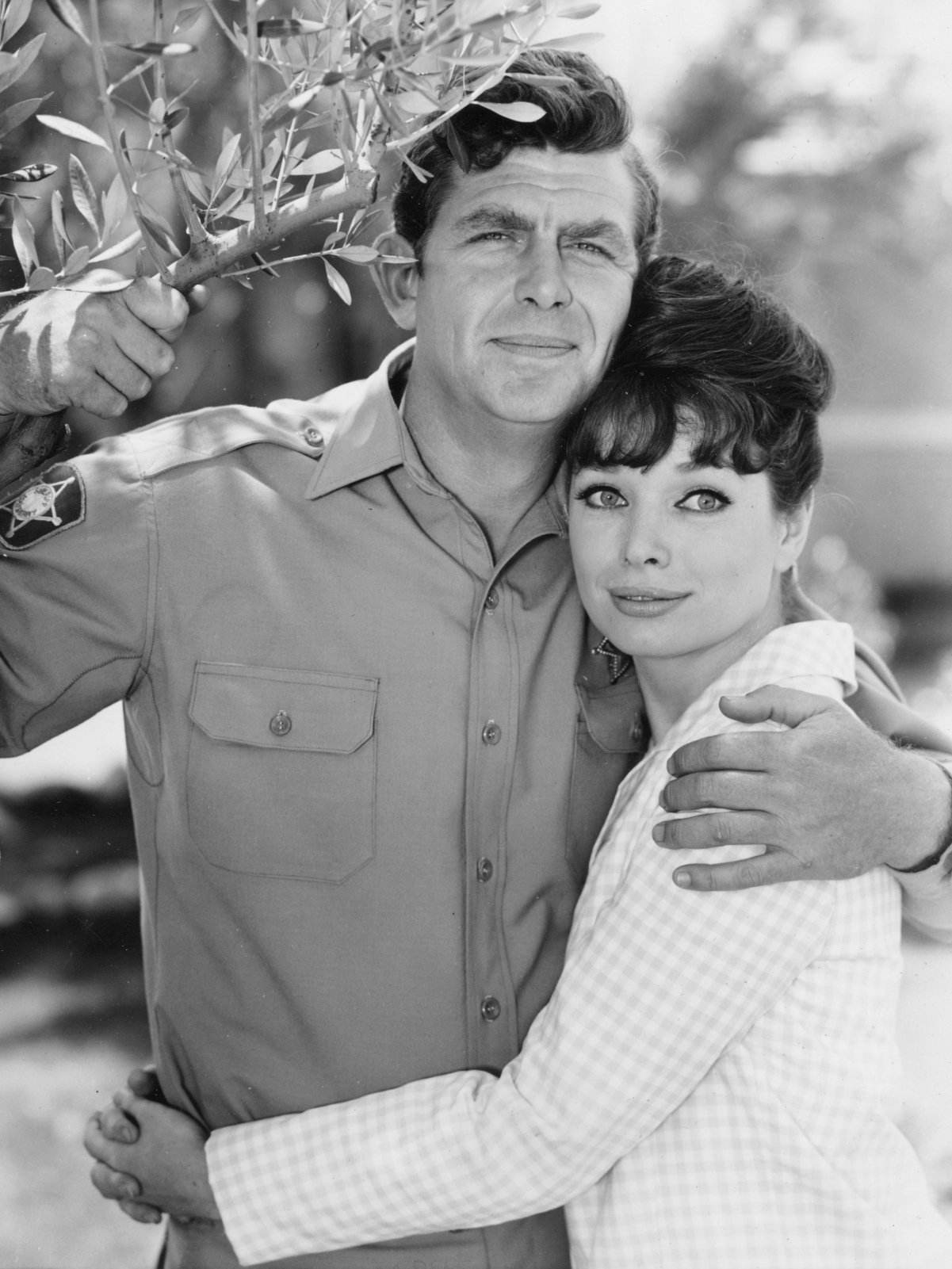 Andy Griffith and Aneta Corsaut stand next to a tree in an embrace, 1964