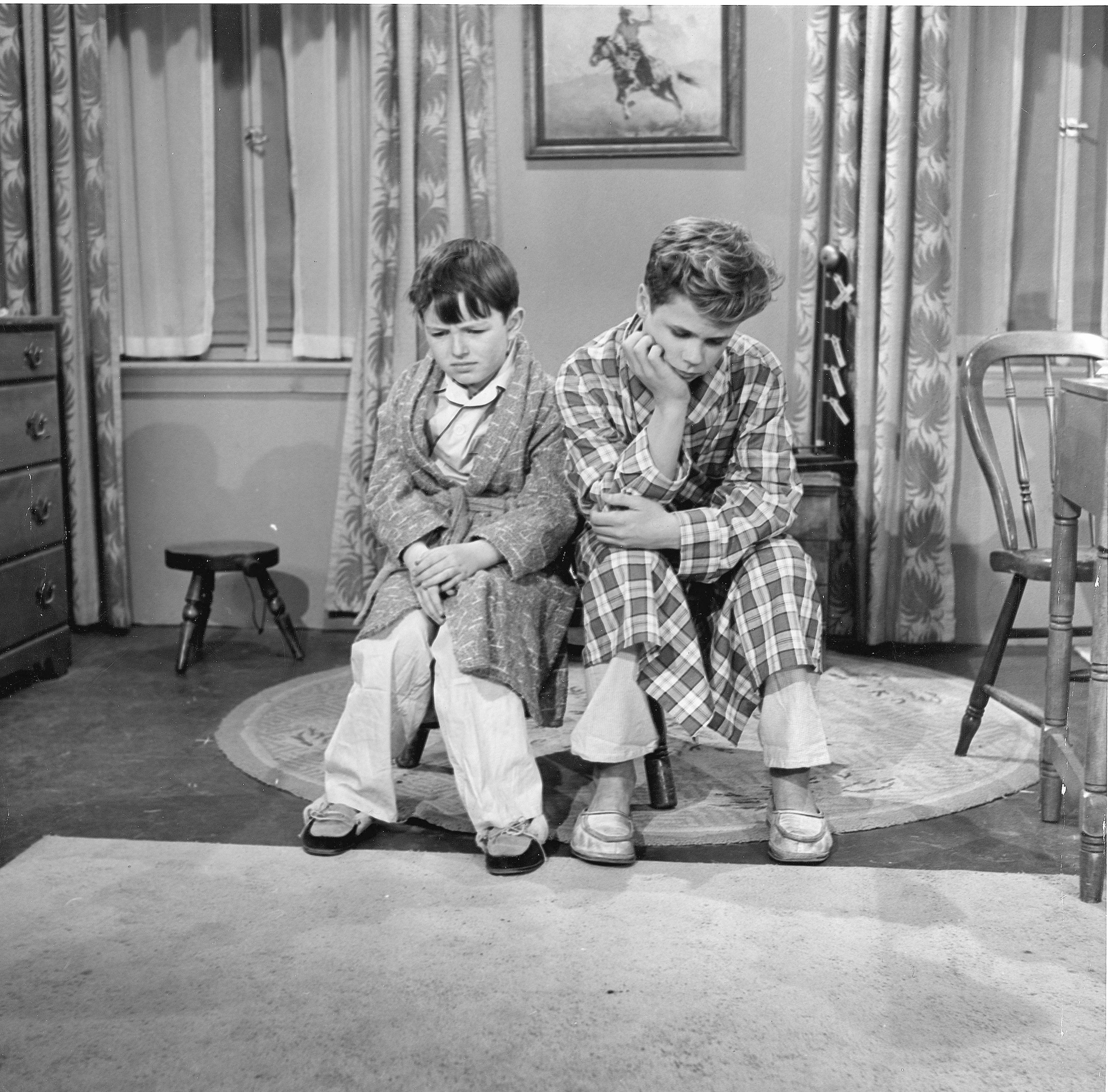 (L to R): Jerry Mathers as Beaver Cleaver and Tony Dow as Wally Cleaver are dressed in robes and sitting forlornly in a scene from 'Leave It to Beaver'
