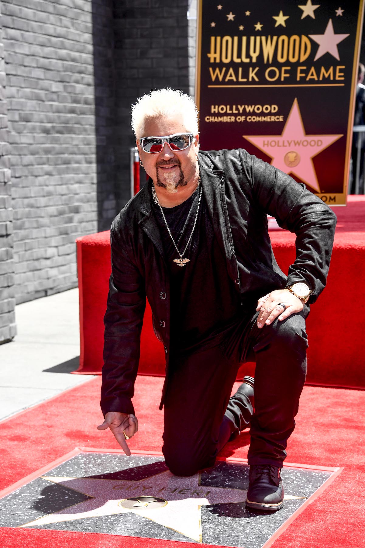 Guy Fieri kneels alongside his Star on the Hollywood Walk of Fame in 2019