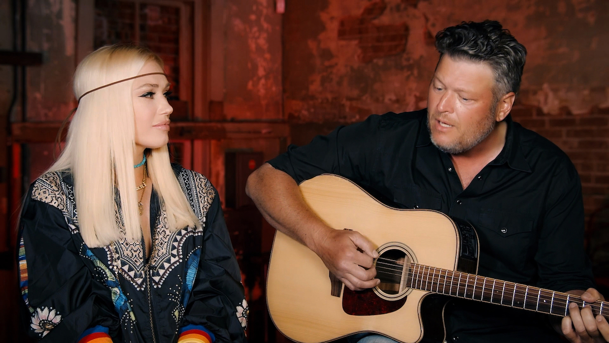 Gwen Stefani looks at Blake Shelton as he sings and plays guitar