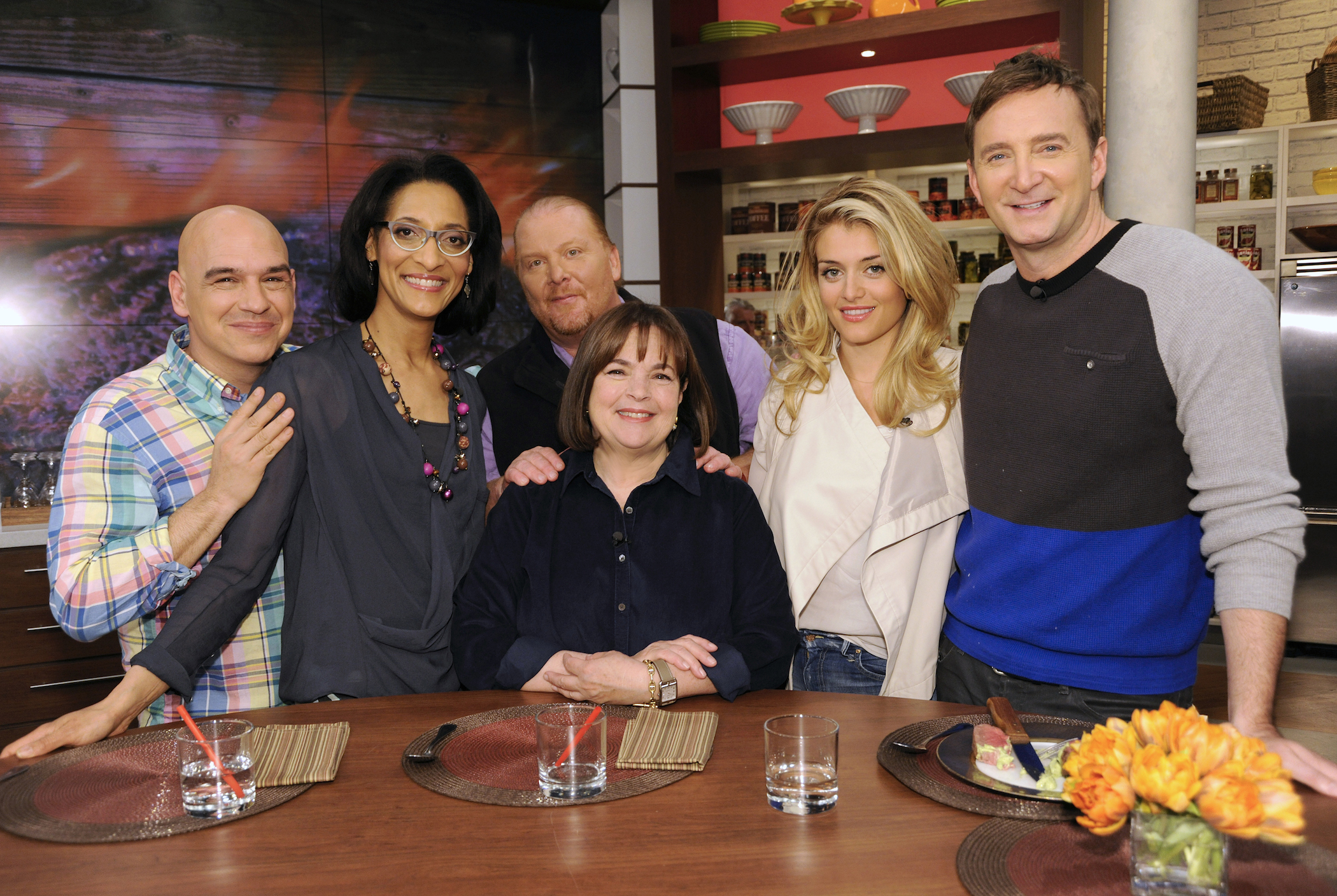 Michael Symon, Carla Hall, Mario Batali, Daphne Oz, and Clinton Kelly surrounding Barefoot Contessa Ina Garten, all smiling at the camera