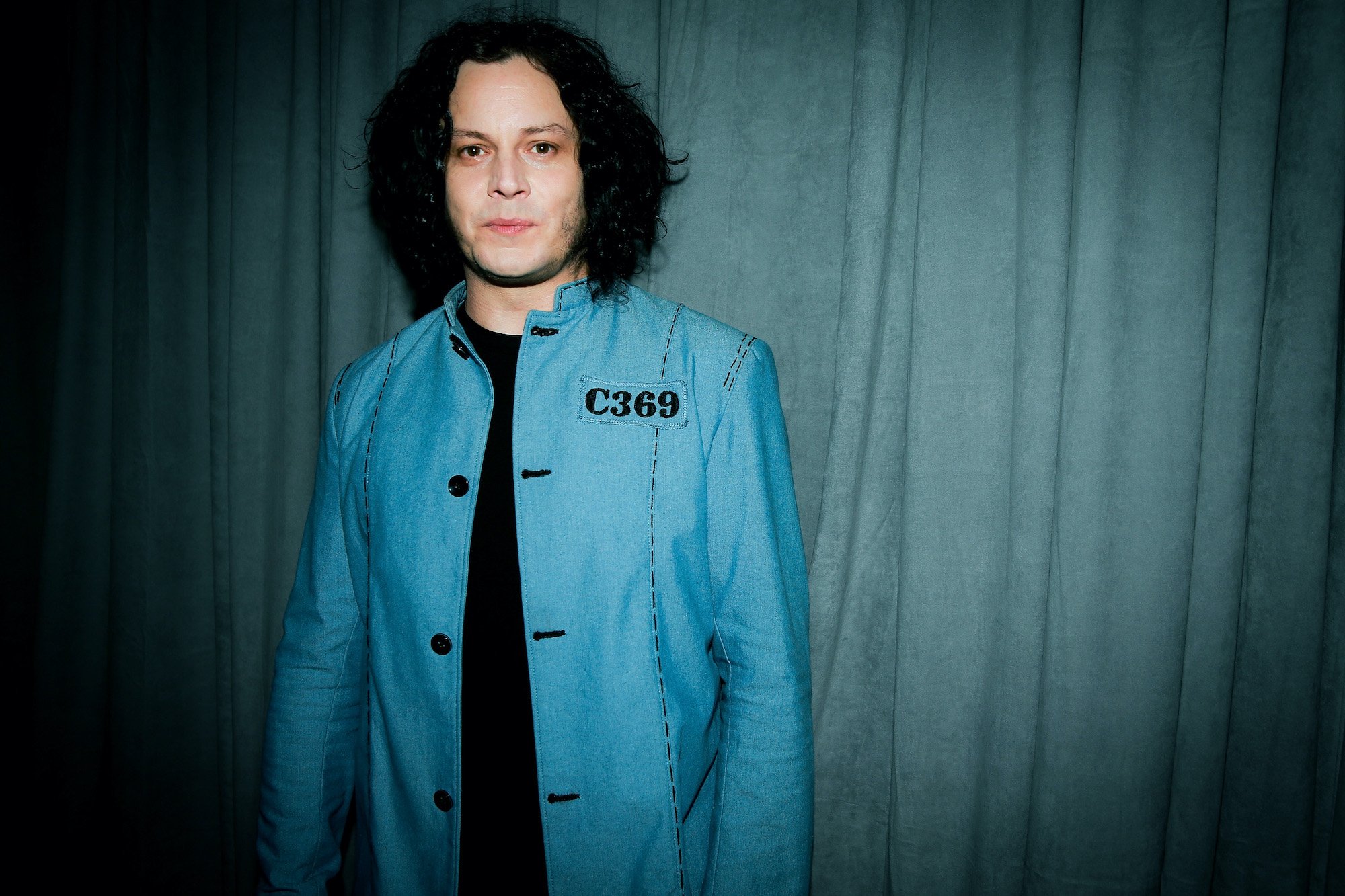 Jack White smiling in front of a green curtain