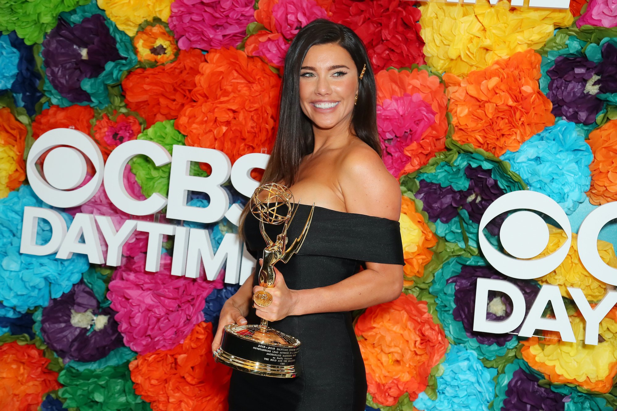Jacqueline MacInnes Wood smiling in front of a multicolored background