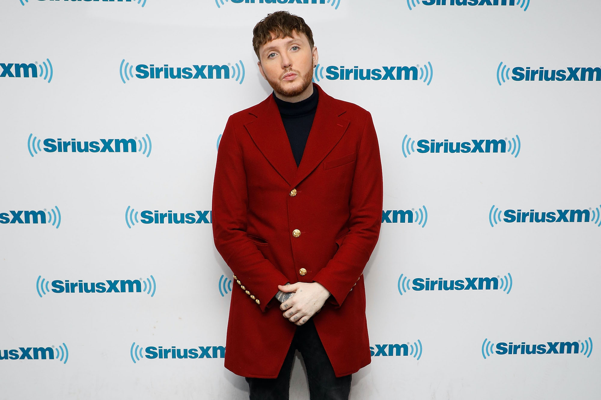 James Arthur smiling in front of a white background