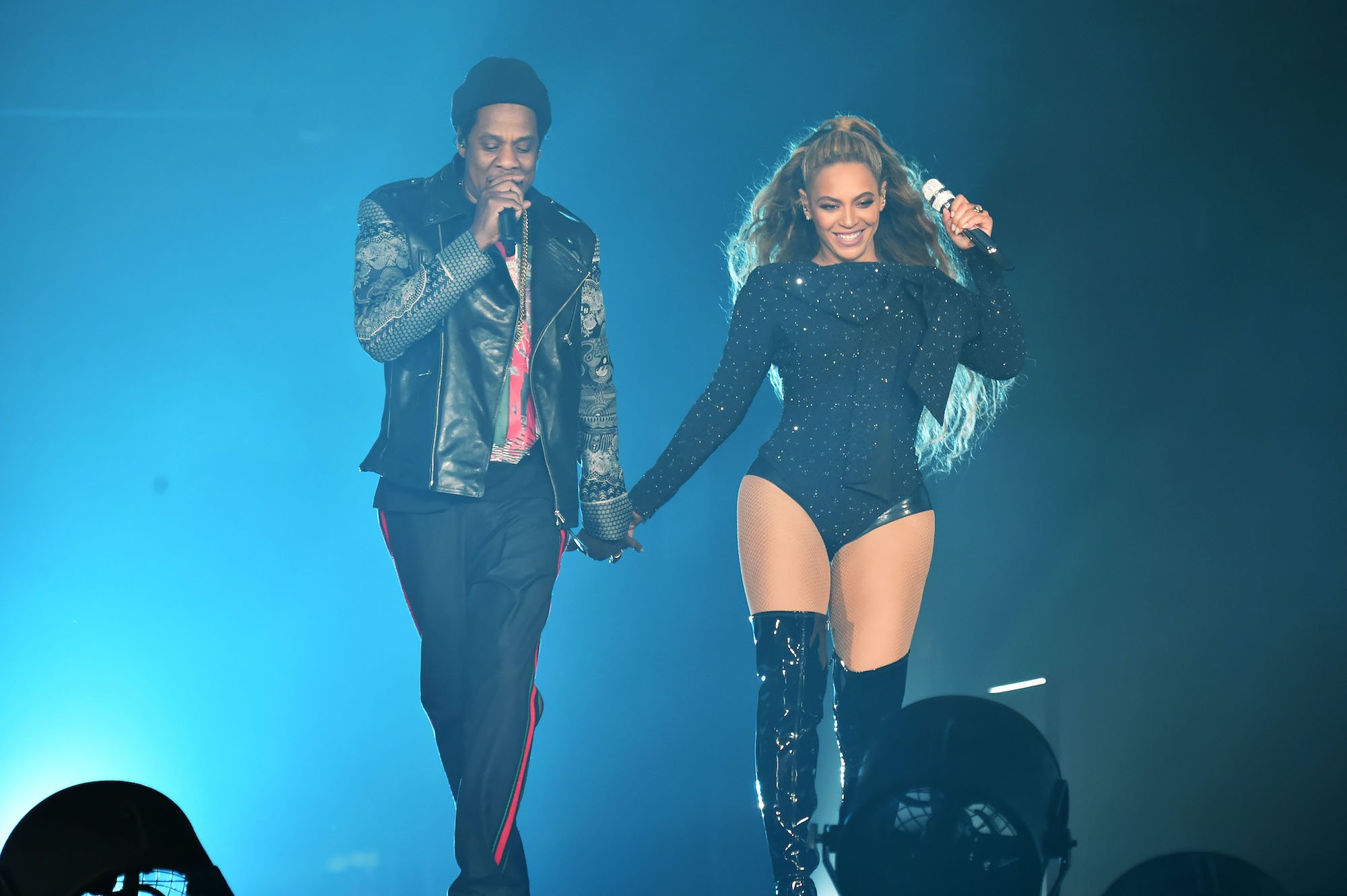 (L-R) Jay-Z and Beyoncé holding hands on stage