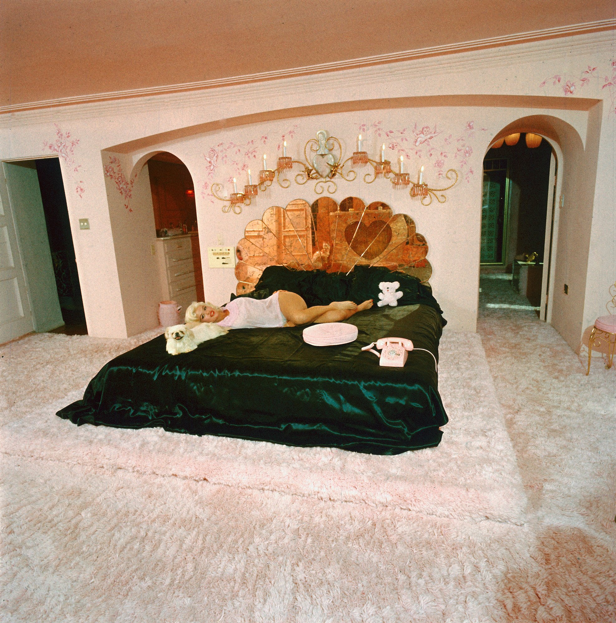 Jayne Mansfield lying on her bed in a light pink room