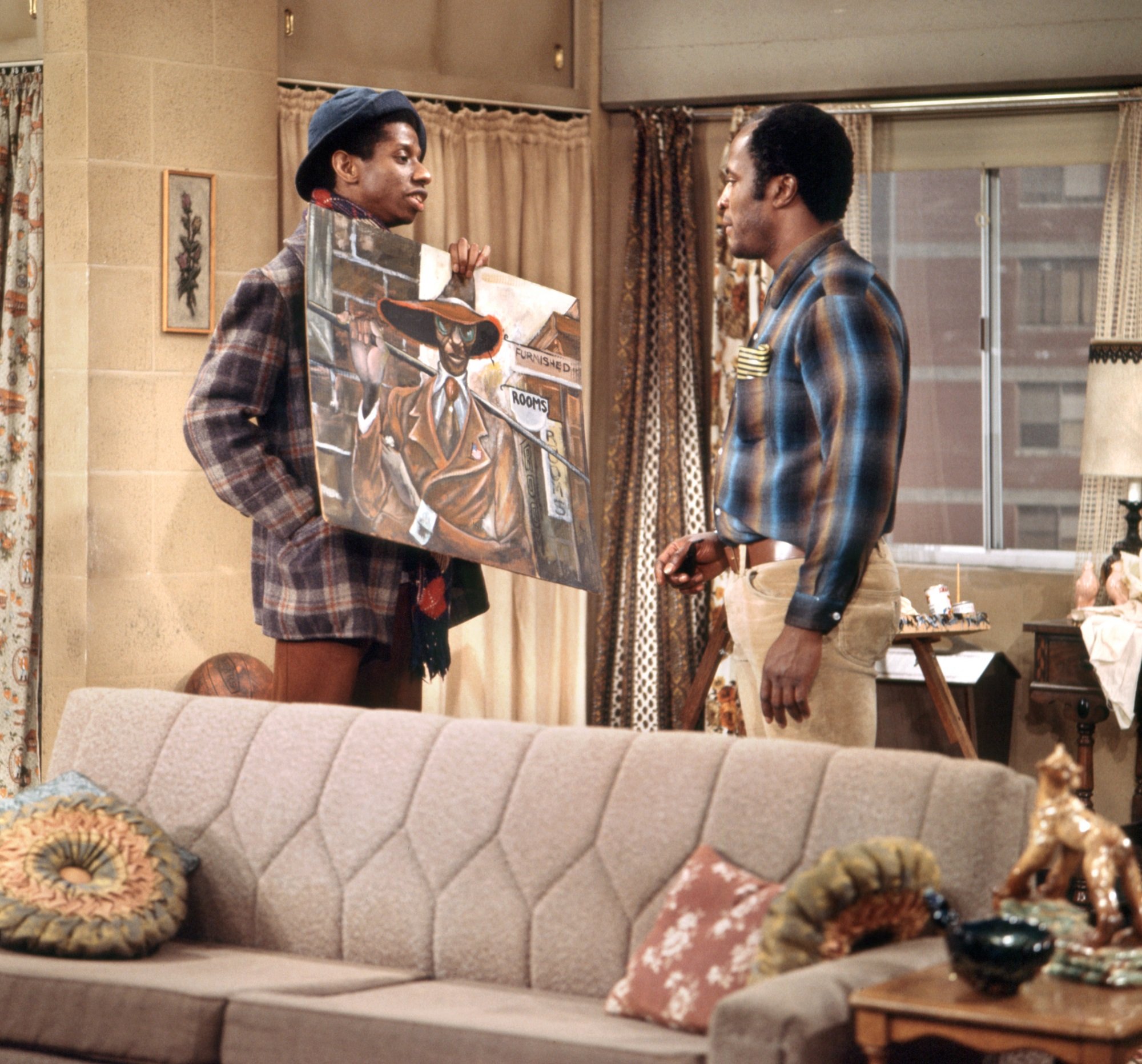 Jimmie Walker holds a painting in front of John Amos