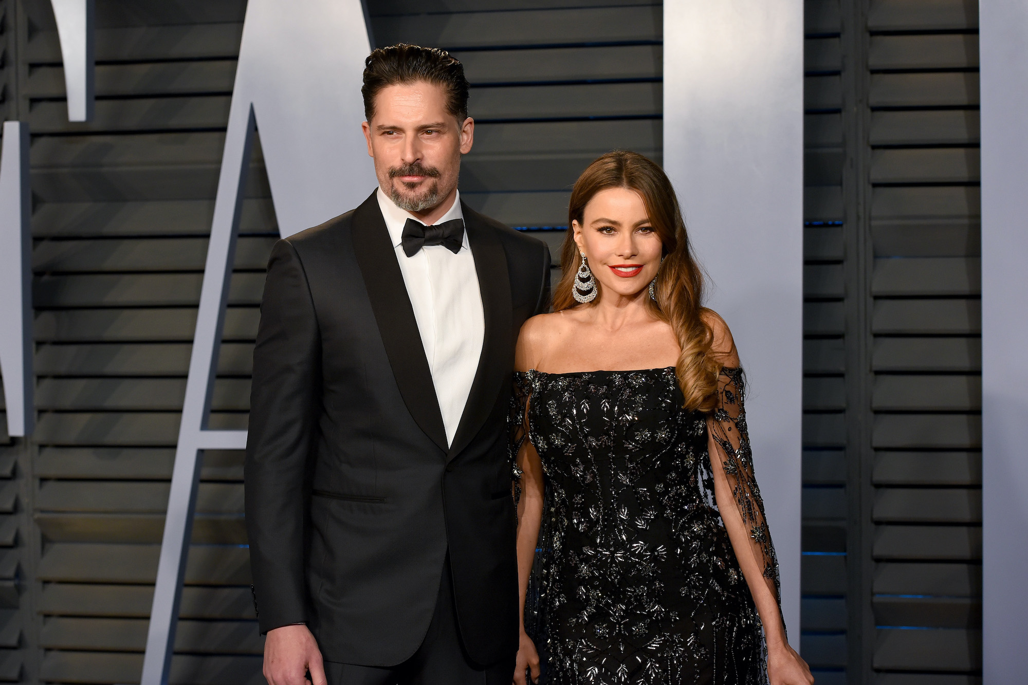 (L-R) Joe Manganiello and Sofia Vergara smiling in front of a gray background