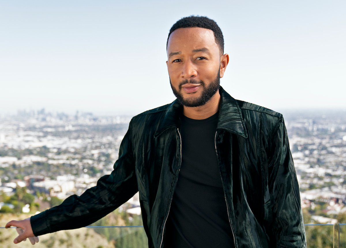 John Legend in a dark green coat standing in front of a city skyline | Troy Harvey/ABC via Getty Images