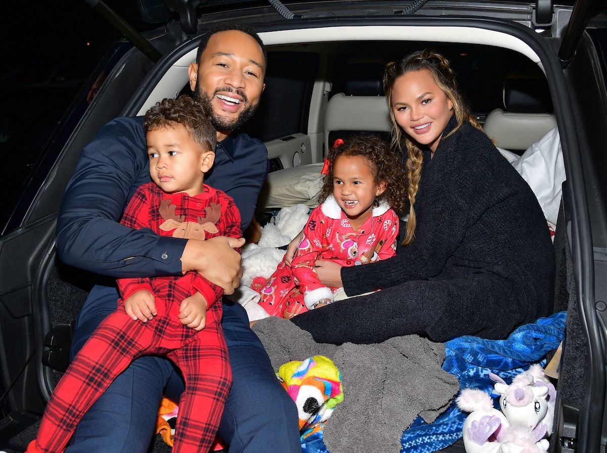 John Legend, Chrissy Teigen, and their children, Luna Stephens and Miles Stephens, sit in the back of a car at Netflix's 'Jingle Jangle: A Christmas Journey' drive-in premiere | Matt Winkelmeyer/Getty Images for Netflix
