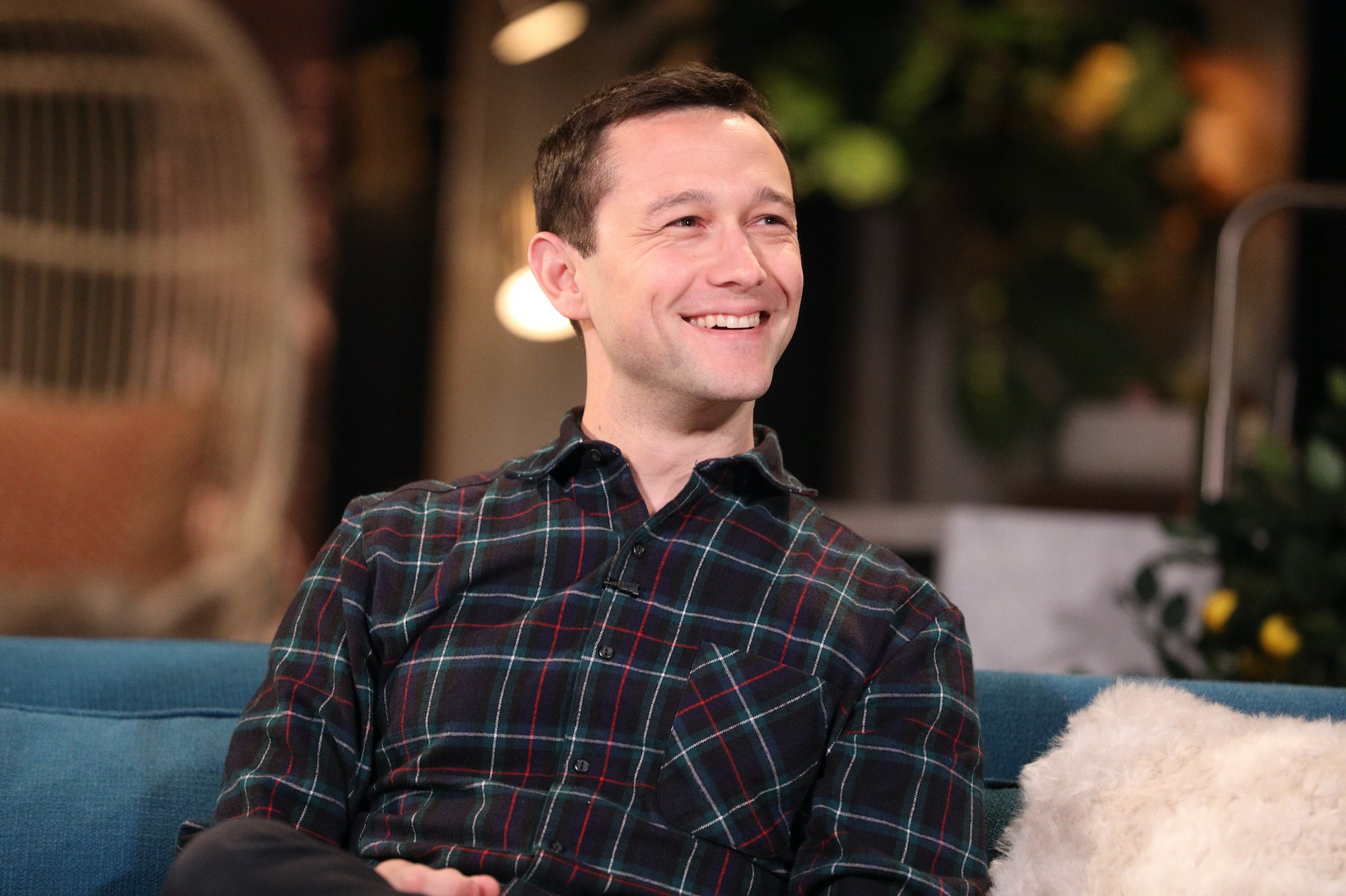 Joseph Gordon-Levitt smiling, sitting on a couch