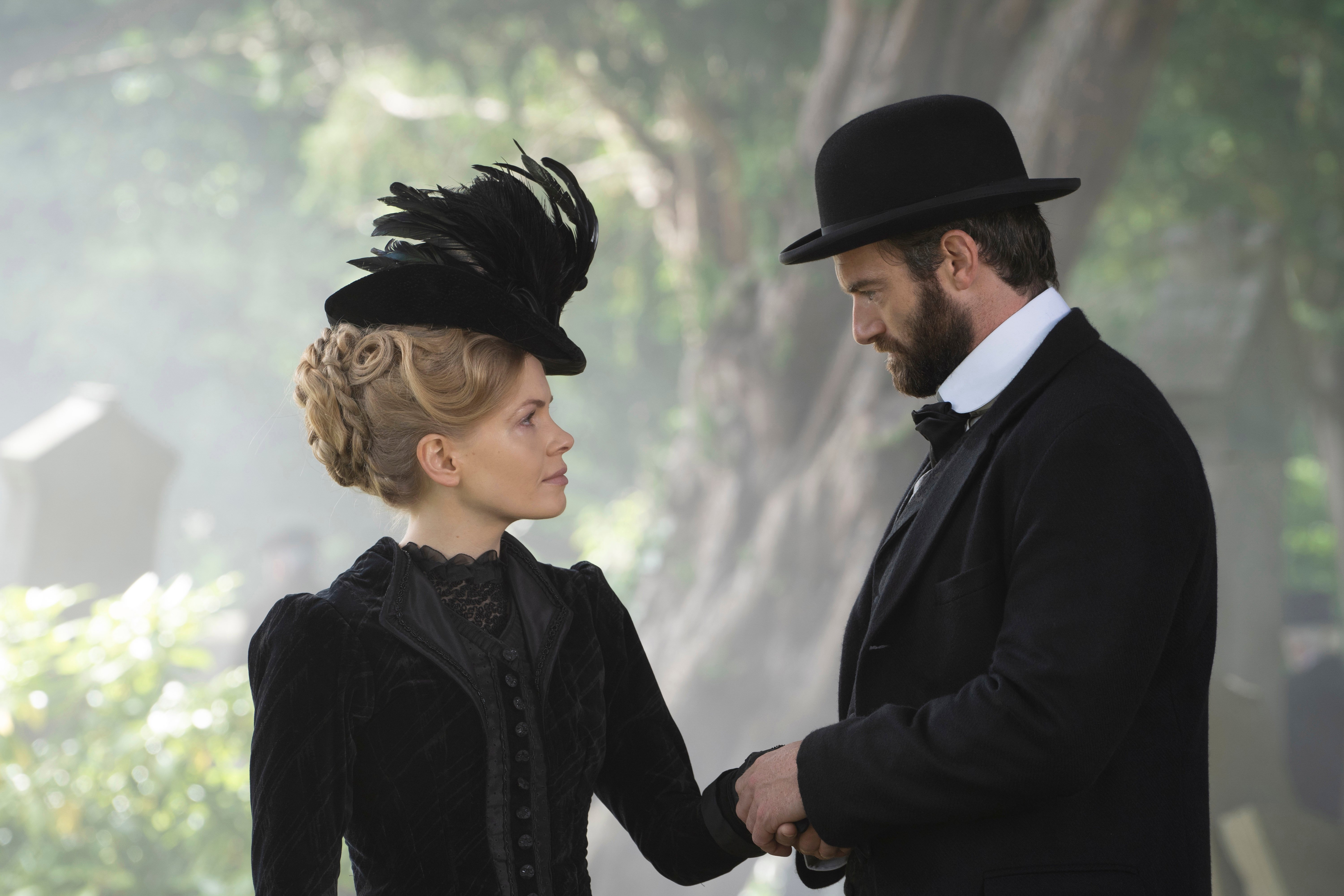 Kate Phillips and Stuart Martin, both dressed in black, looking at each other in an episode of Miss Scarlet and the Duke