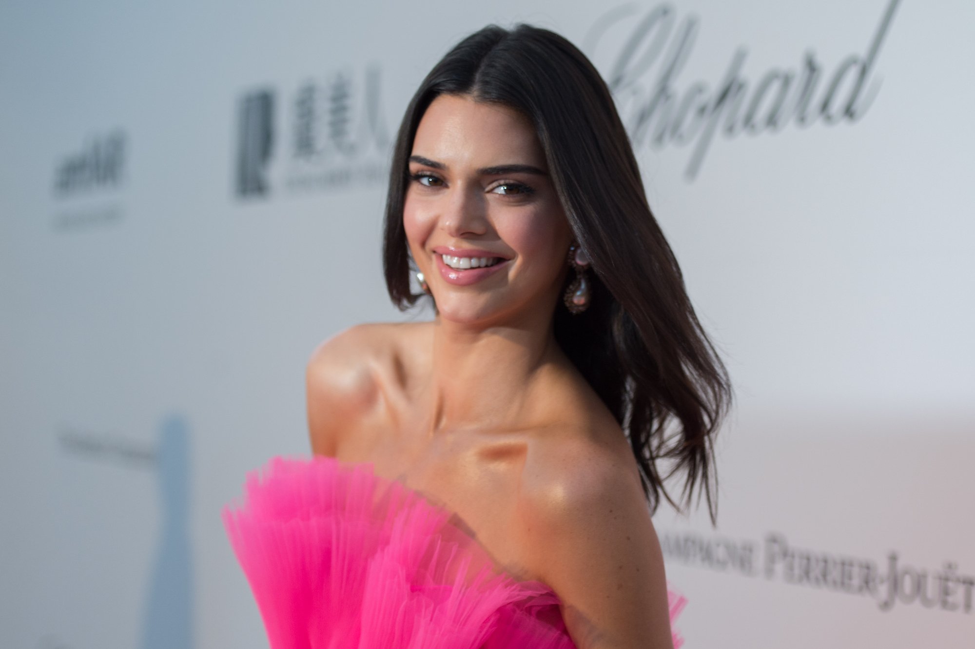 Kendall Jenner smiling in front of a white background