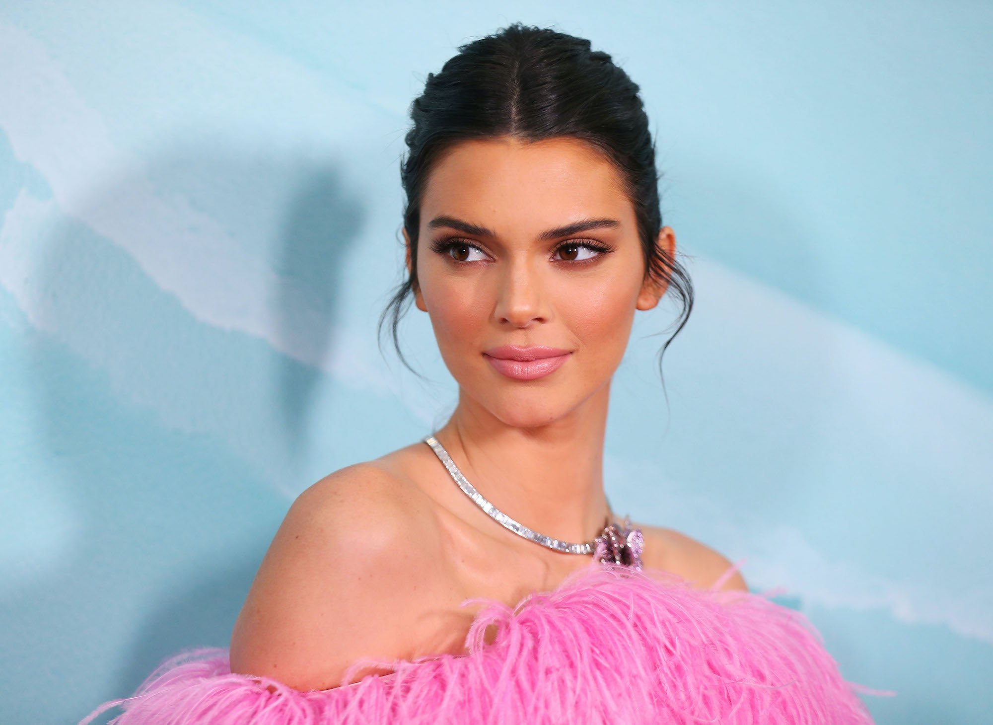 Kendall Jenner smiling in front of a blue background