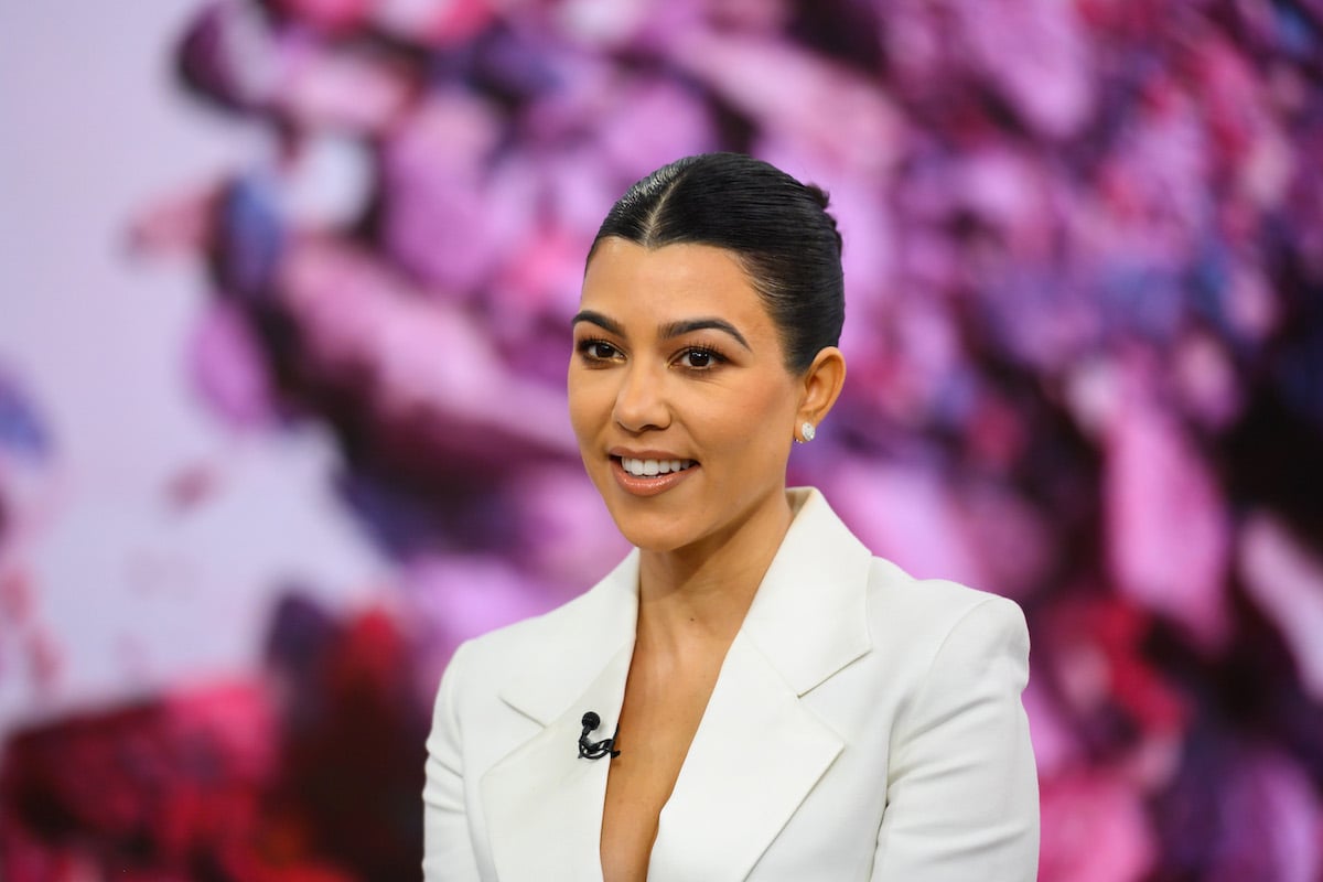 Kourtney Kardashian smiling wearing a white suit