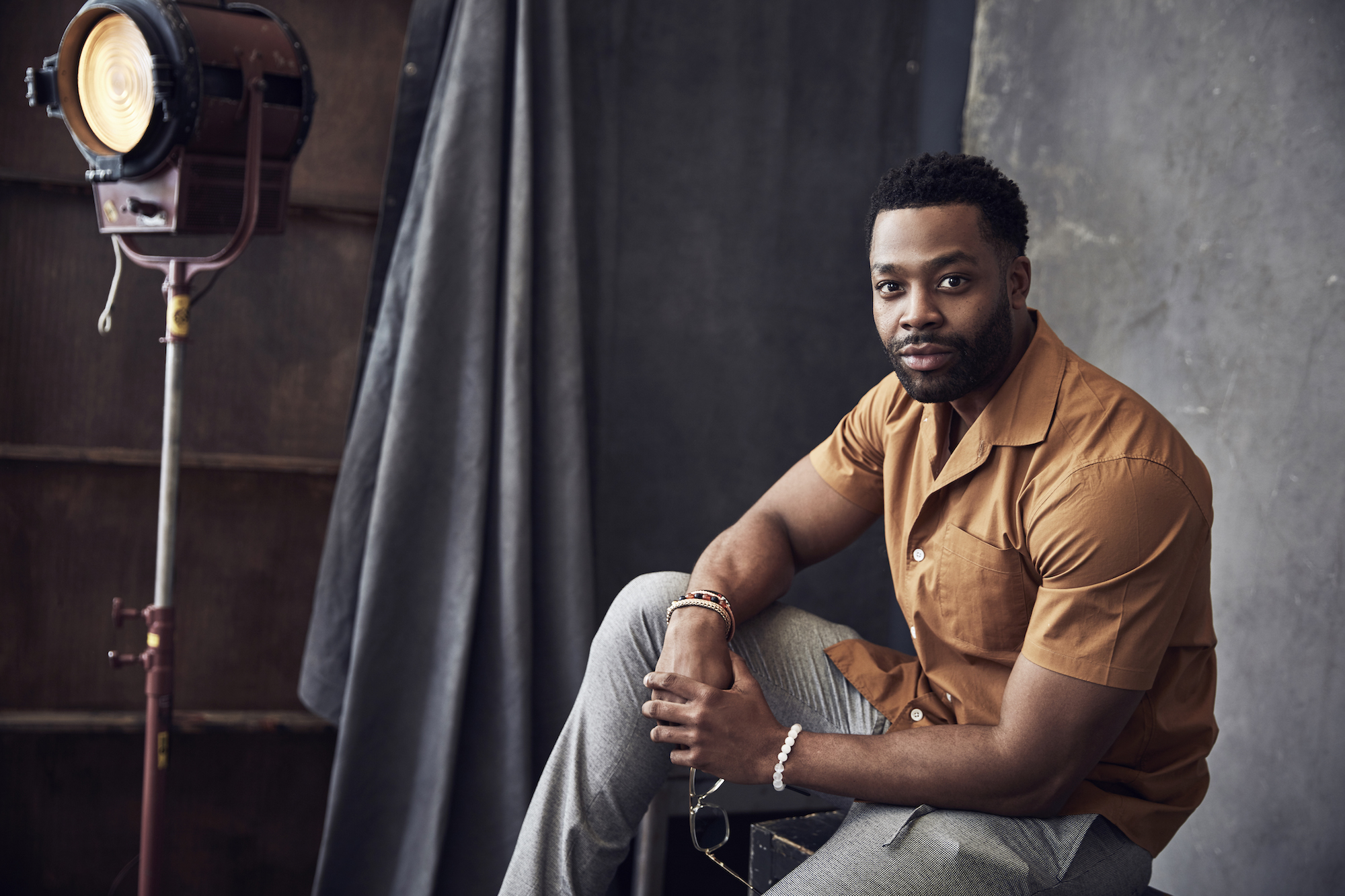 LaRoyce Hawkins smiling, posed on a block in front of a gray background and vintage photography light