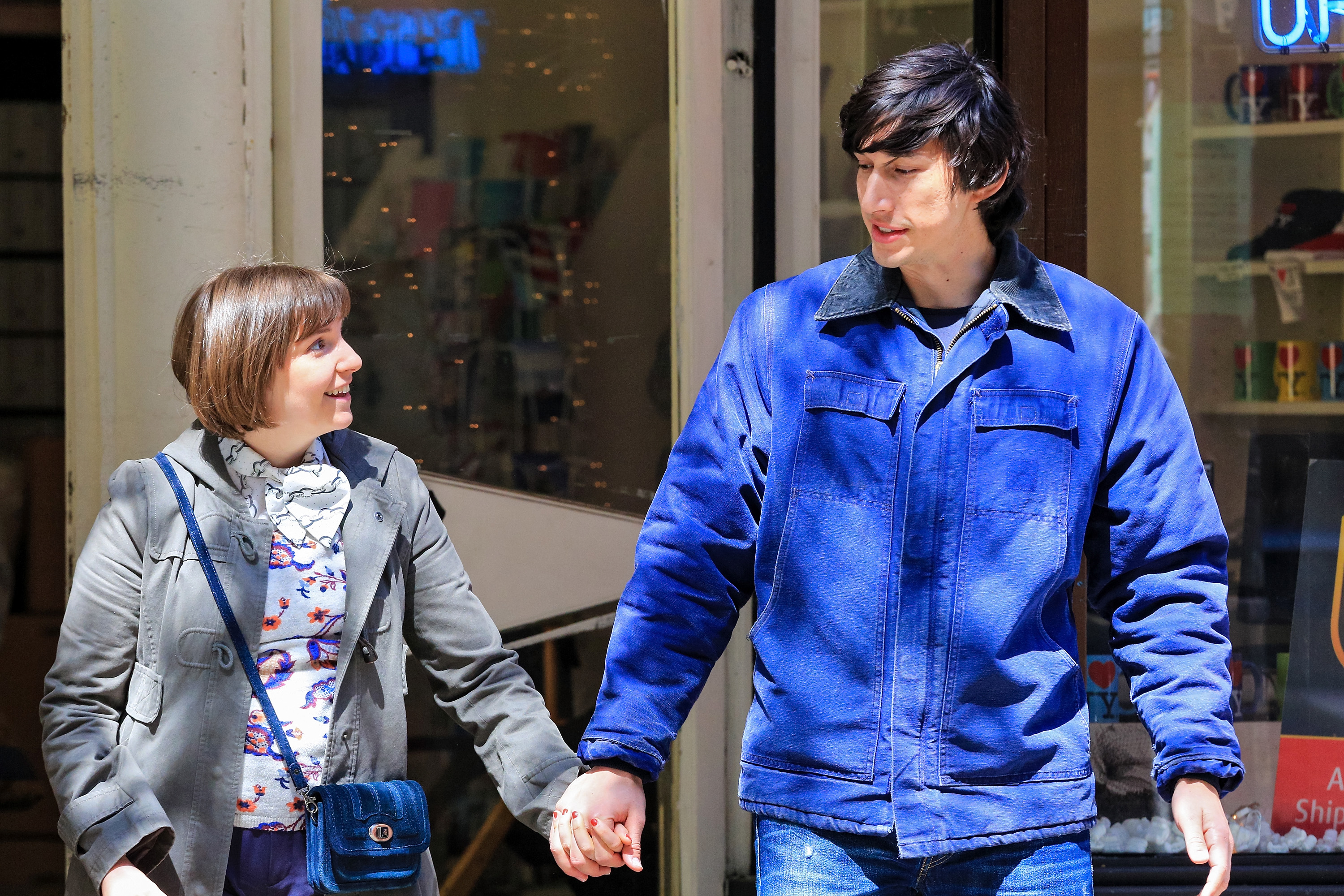 Lena Dunham and Adam Driver filming 'Girls.' They're walking down the street holding hands.
