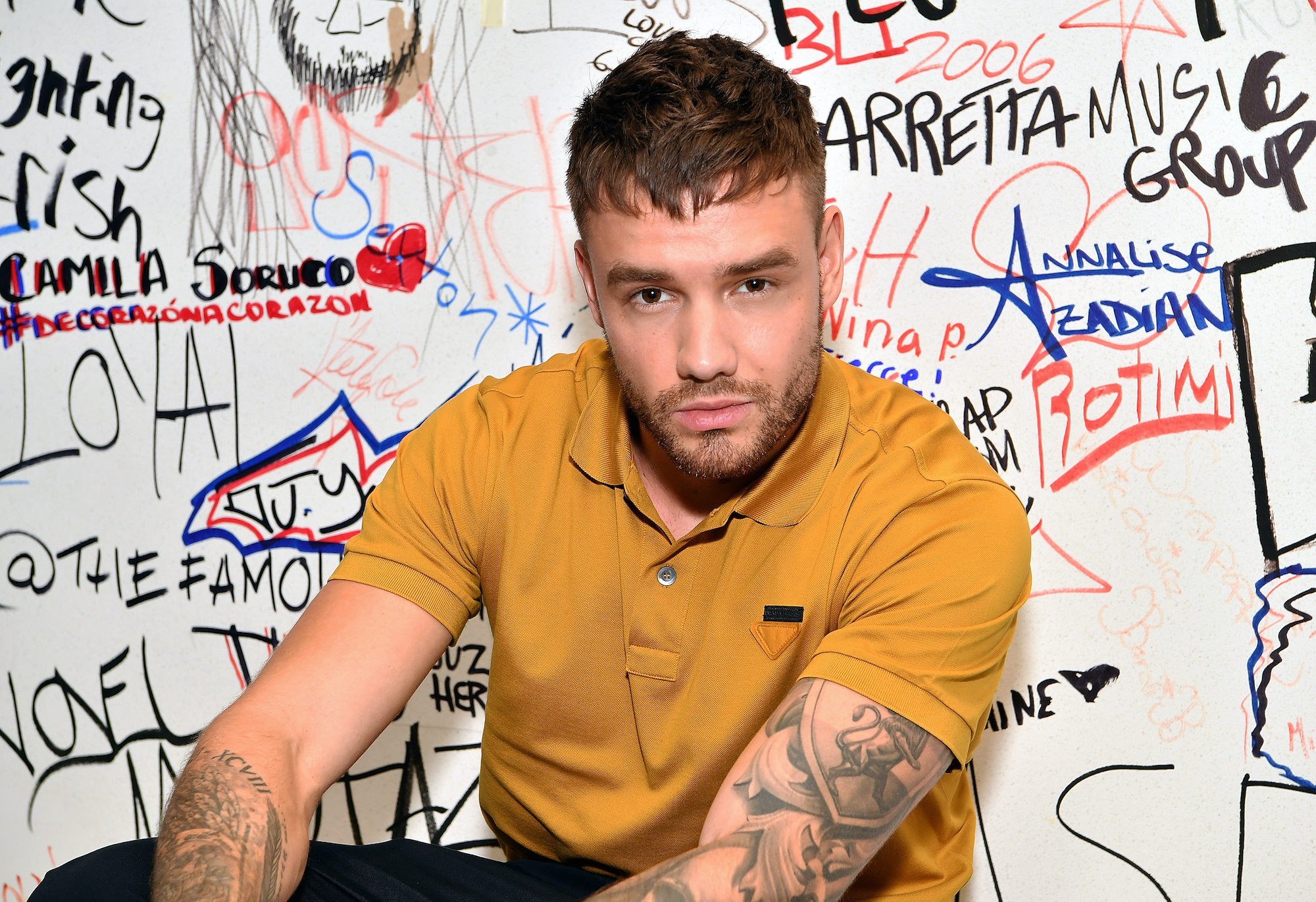 Liam Payne sitting in front of a wall covered in writing