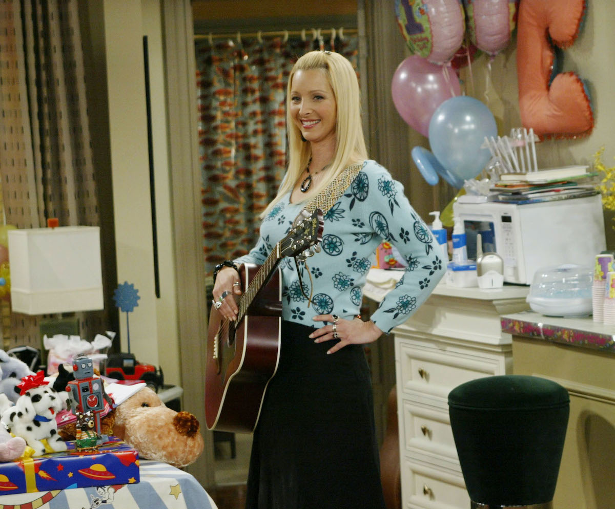 Lisa Kudrow as Phoebe Buffay on 'Friends' stands with a guitar at a party.