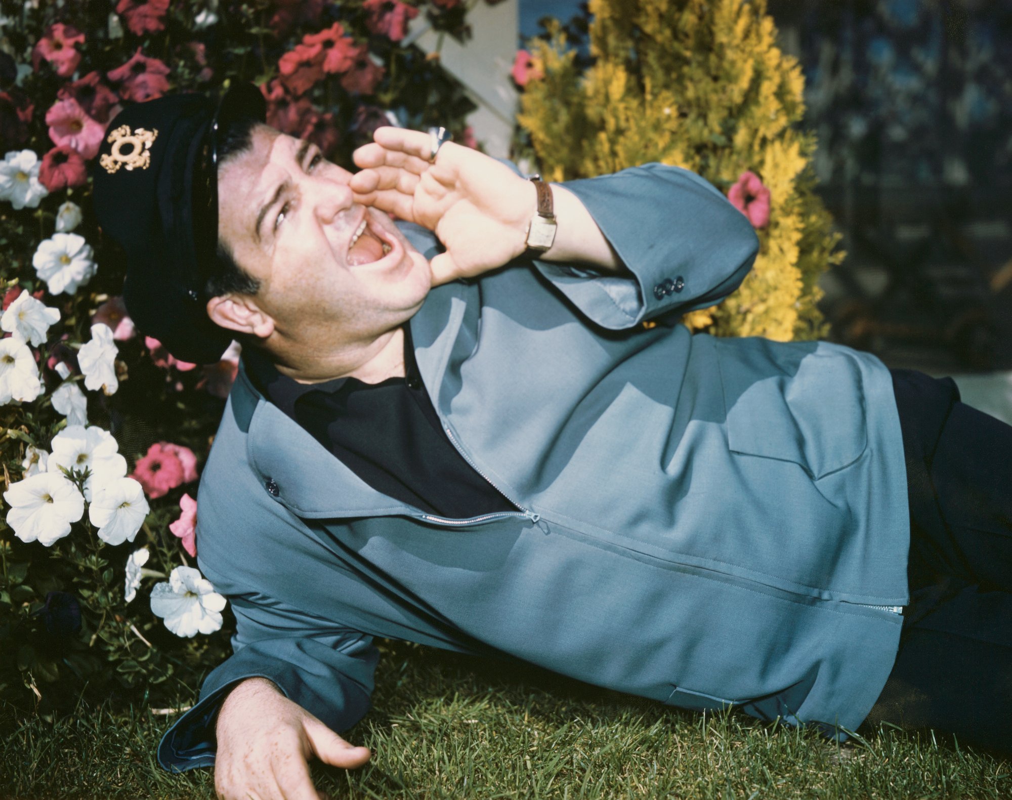 Lou Costello lying on the grass, shouting, head turned up to the right