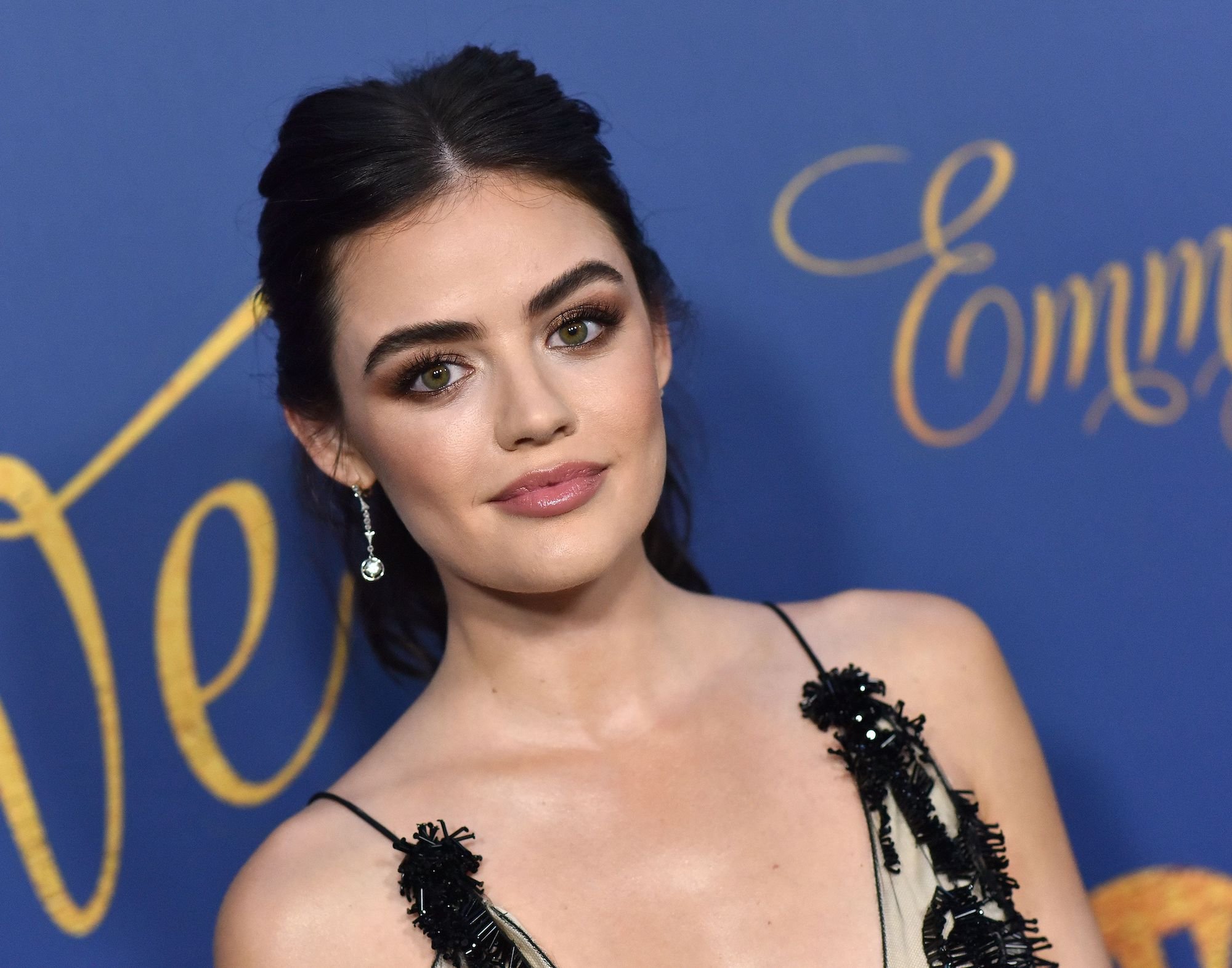 Lucy Hale smiling in front of a blue background