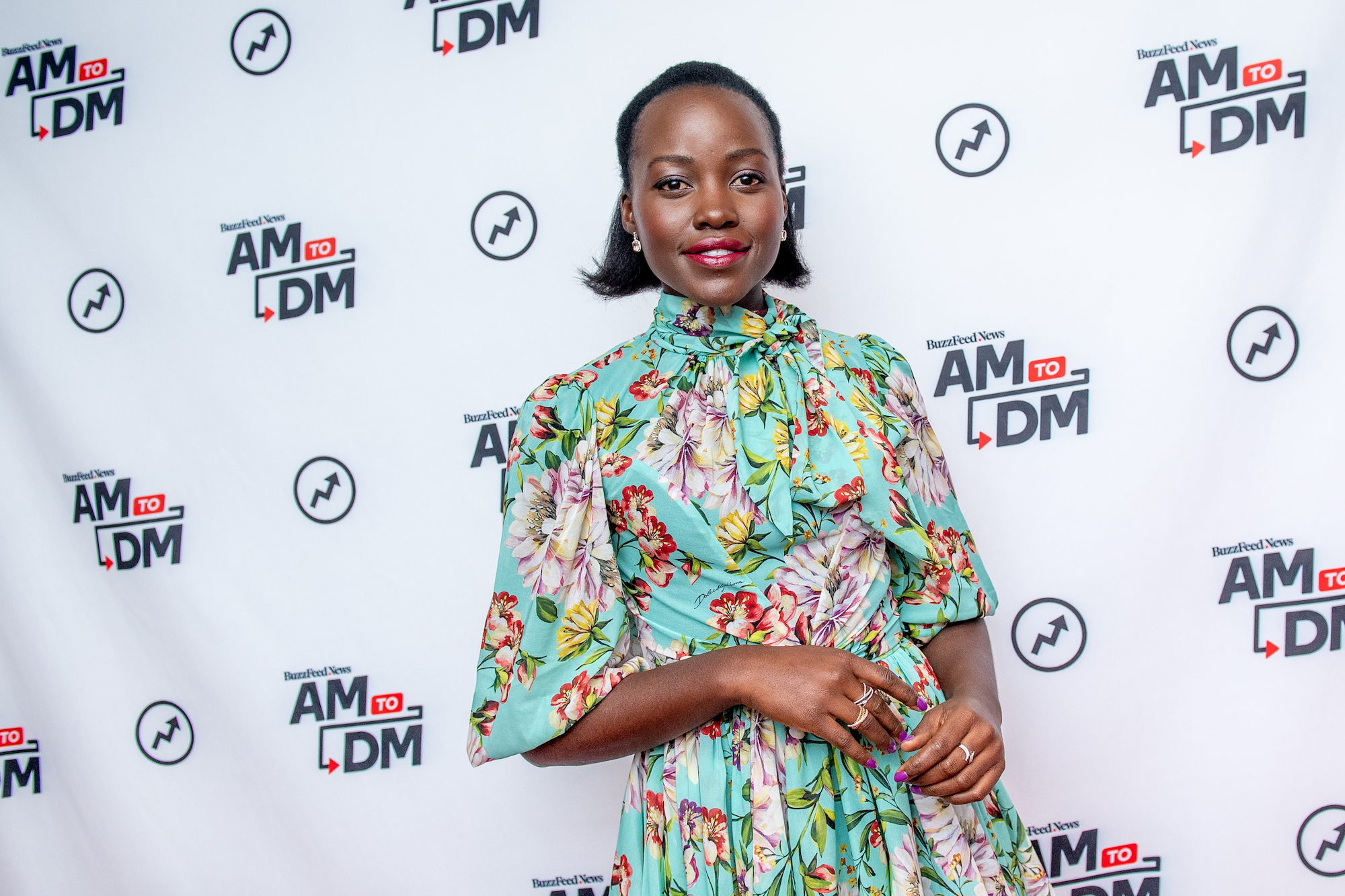 Lupita Nyong'o smiling in front of a white background