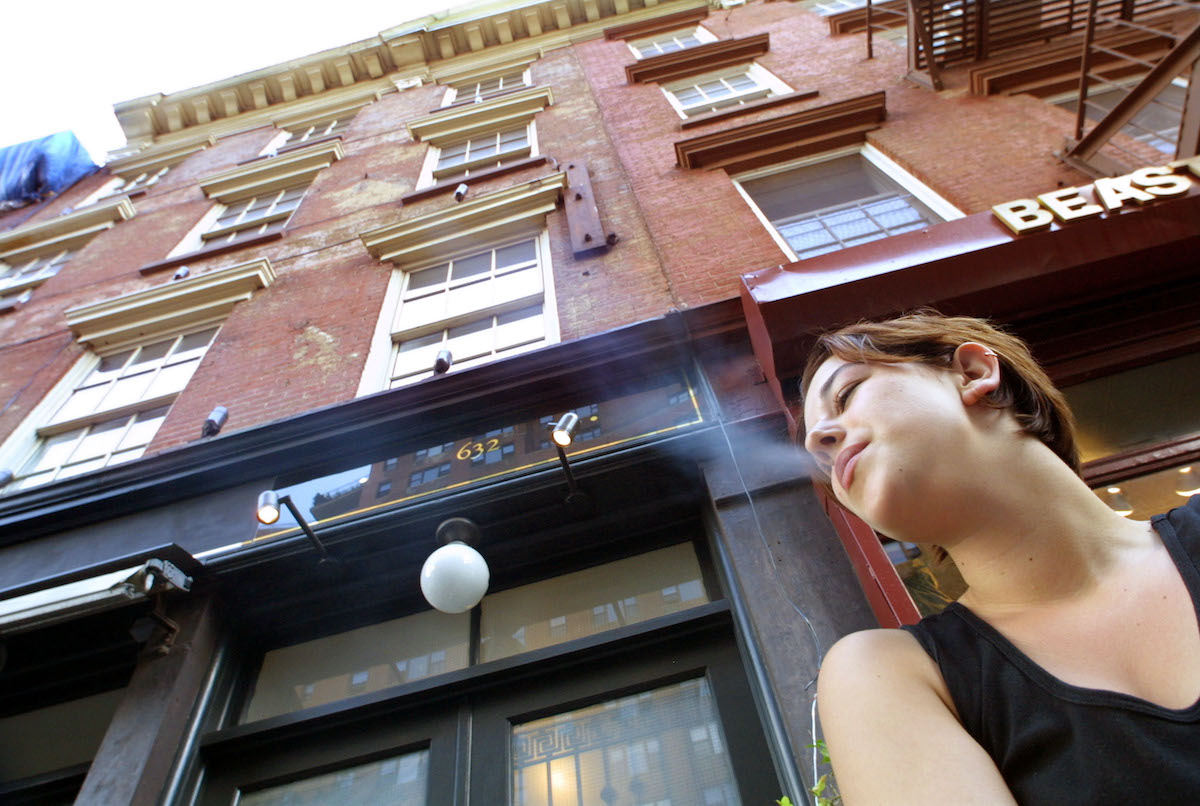 A woman smokes a cigarette in front of the house where the cast from MTV''s 'The Real World' lived July 11, 2001 in New York City