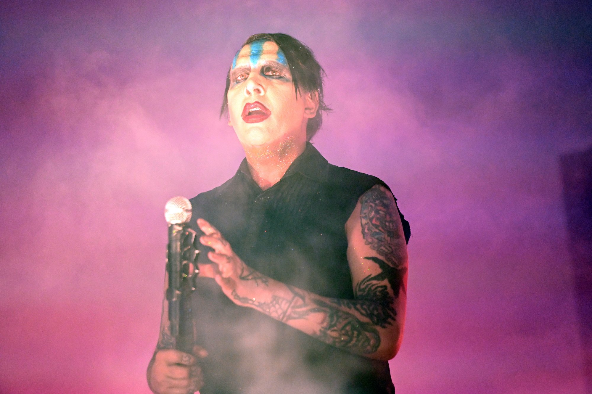 Marilyn Manson on stage in front of a pink and purple background