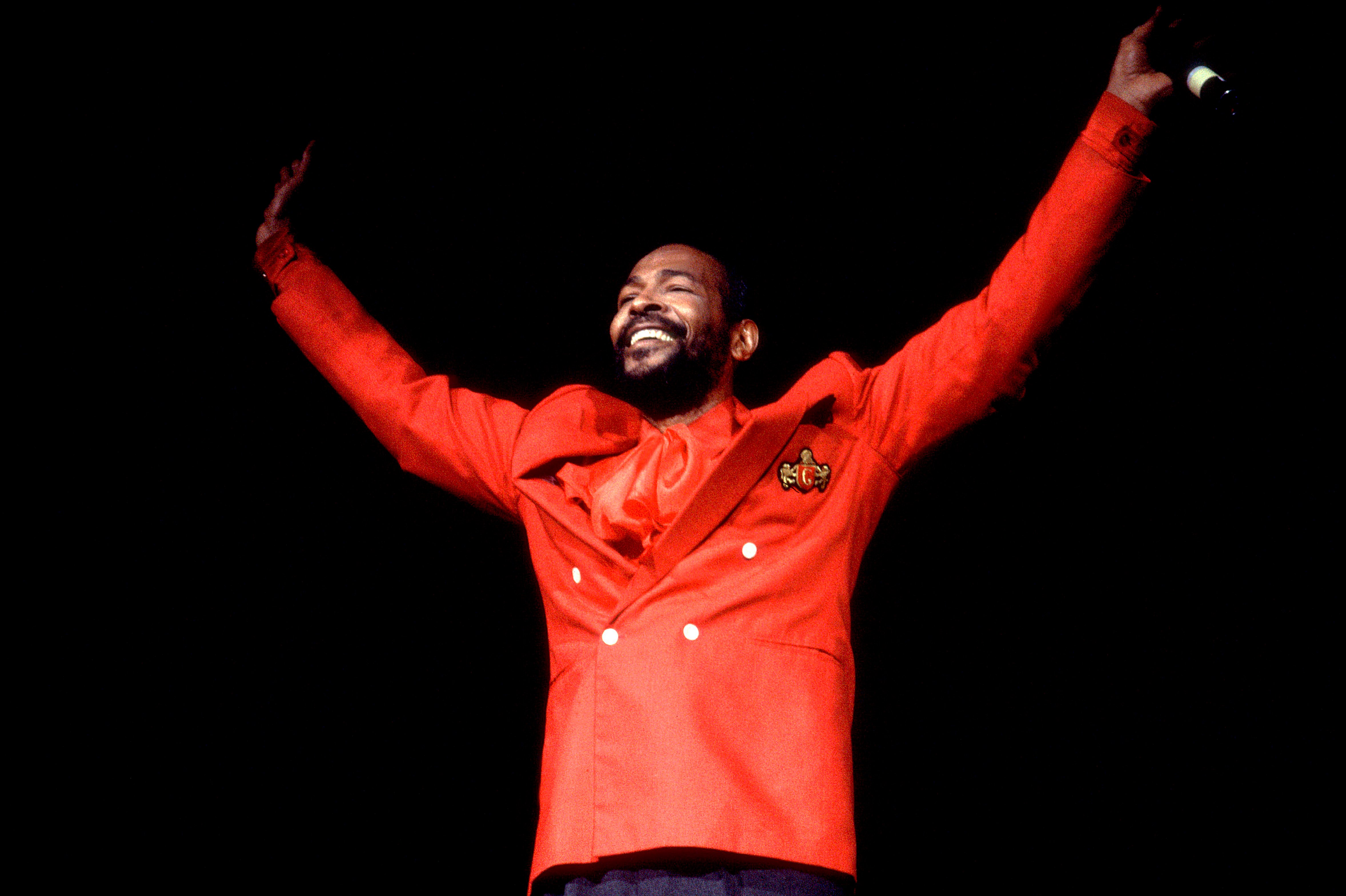 Marvin Gaye raising his hands onstage after a performance in 1983