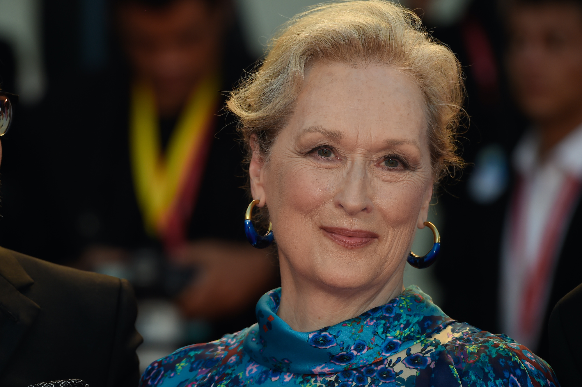 Meryl Streep smiling in front of a blurred crowd