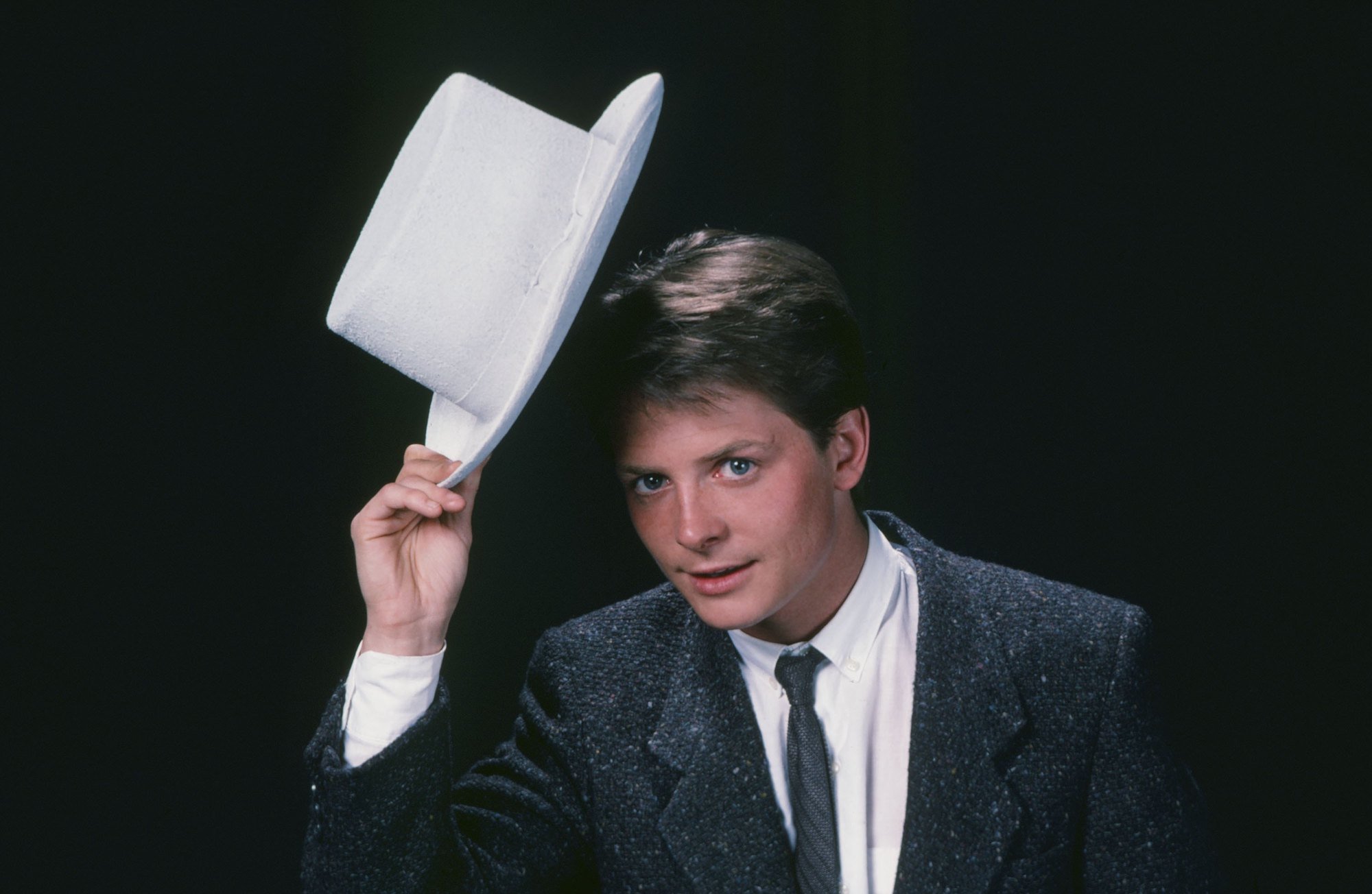 Michael J. Fox as Alex P. Keaton, tipping a top hat