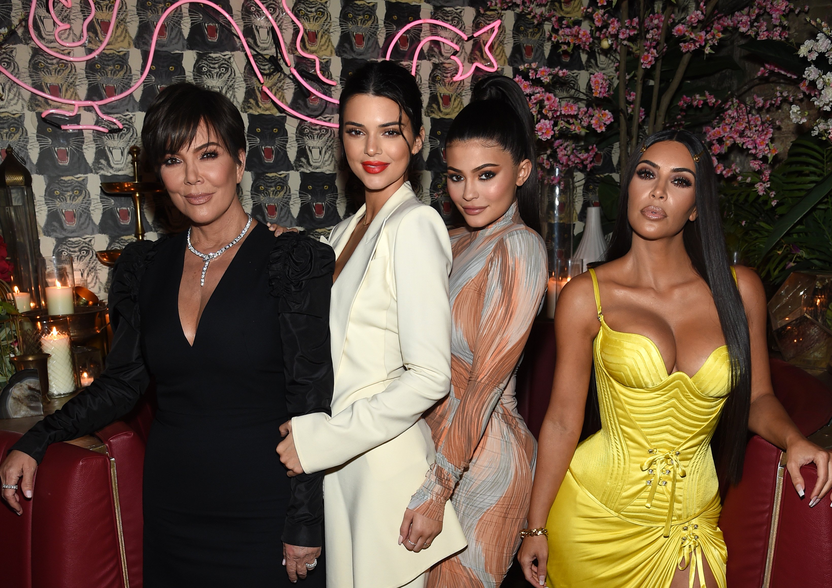 Momager Kris Jenner smiling at dinner party while standing next to three of her daughters Kendall Jenner, Kylie Jenner, and Kim Kardashian West