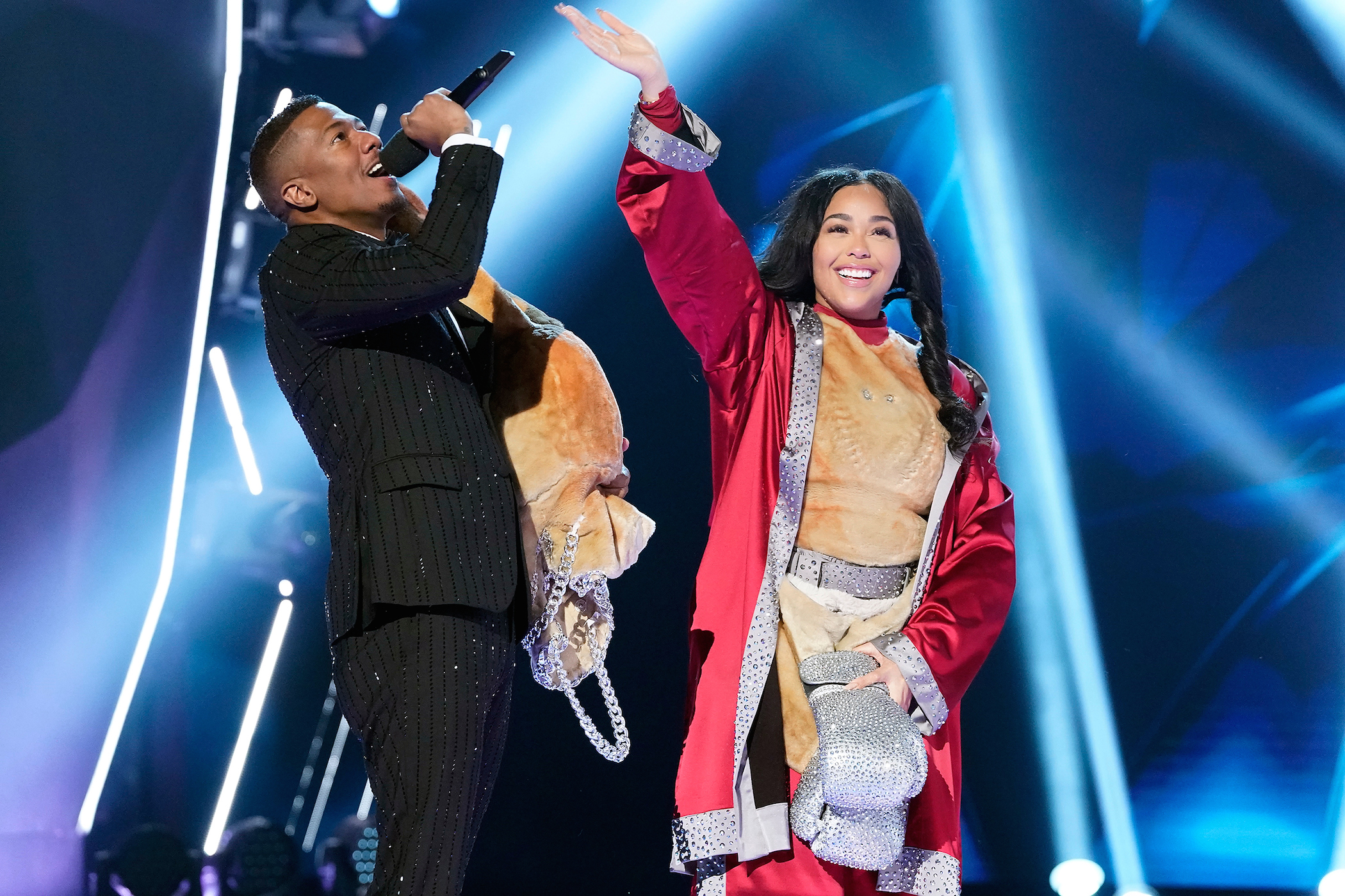 Nick Cannon next to 'Masked Singer' star Jordyn Woods waving to the cameras on 'The Masked Singer'
