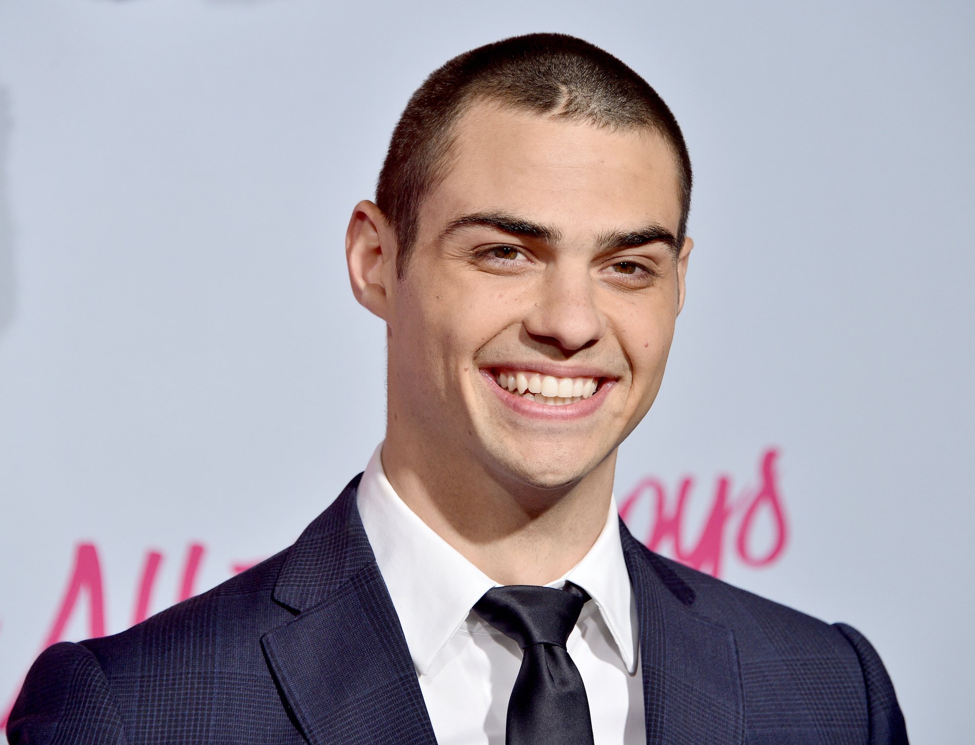 Noah Centineo smiling in front of a white background