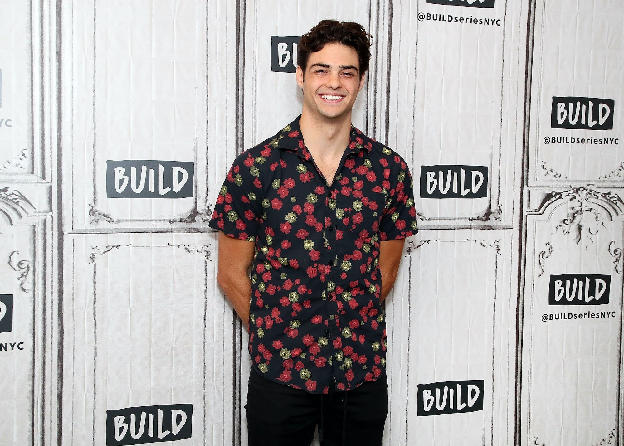 Noah Centineo smiling in front of a white background