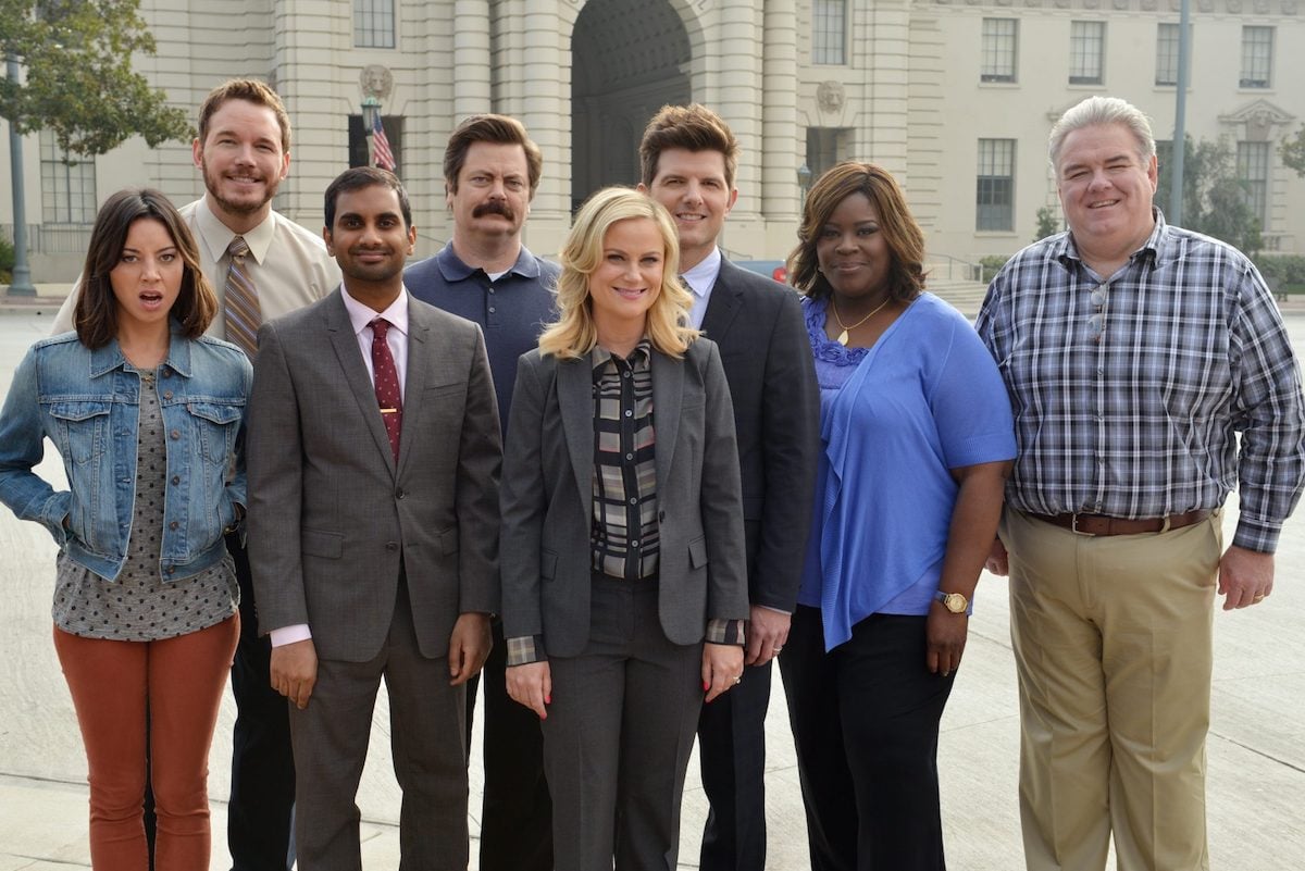 The cast of 'Parks and Rec' Season 6 stands and smiles outside a government building