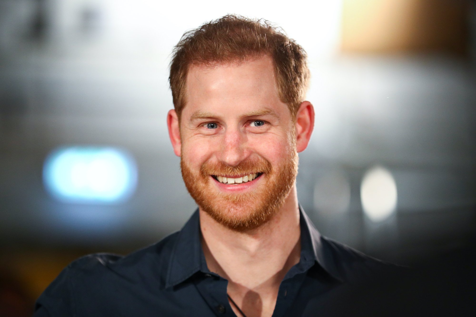 Prince Harry smiling in front of a blurred background