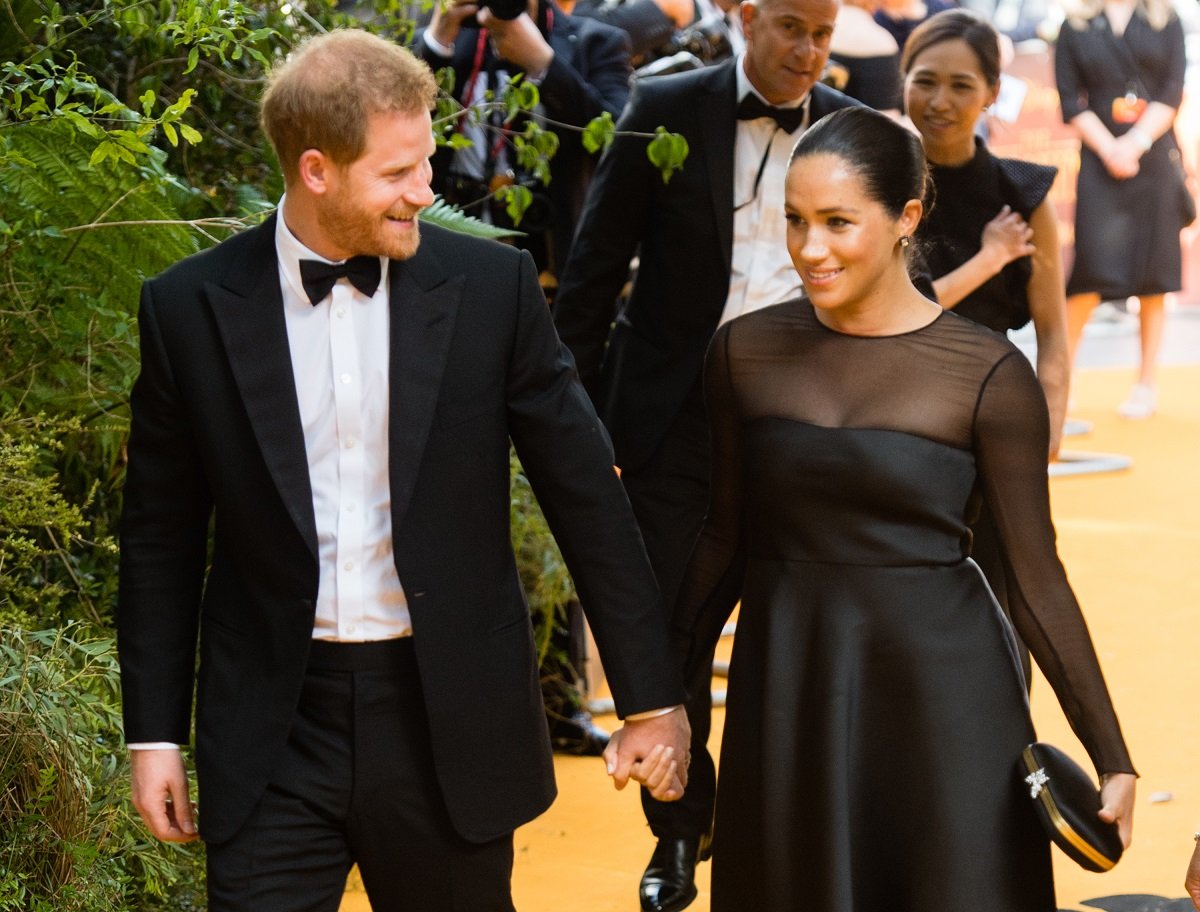 Prince Harry, Duke of Sussex, and Meghan, Duchess of Sussex, holding hands on the red carpet at the 'Lion King' European Premiere in 2019 in London