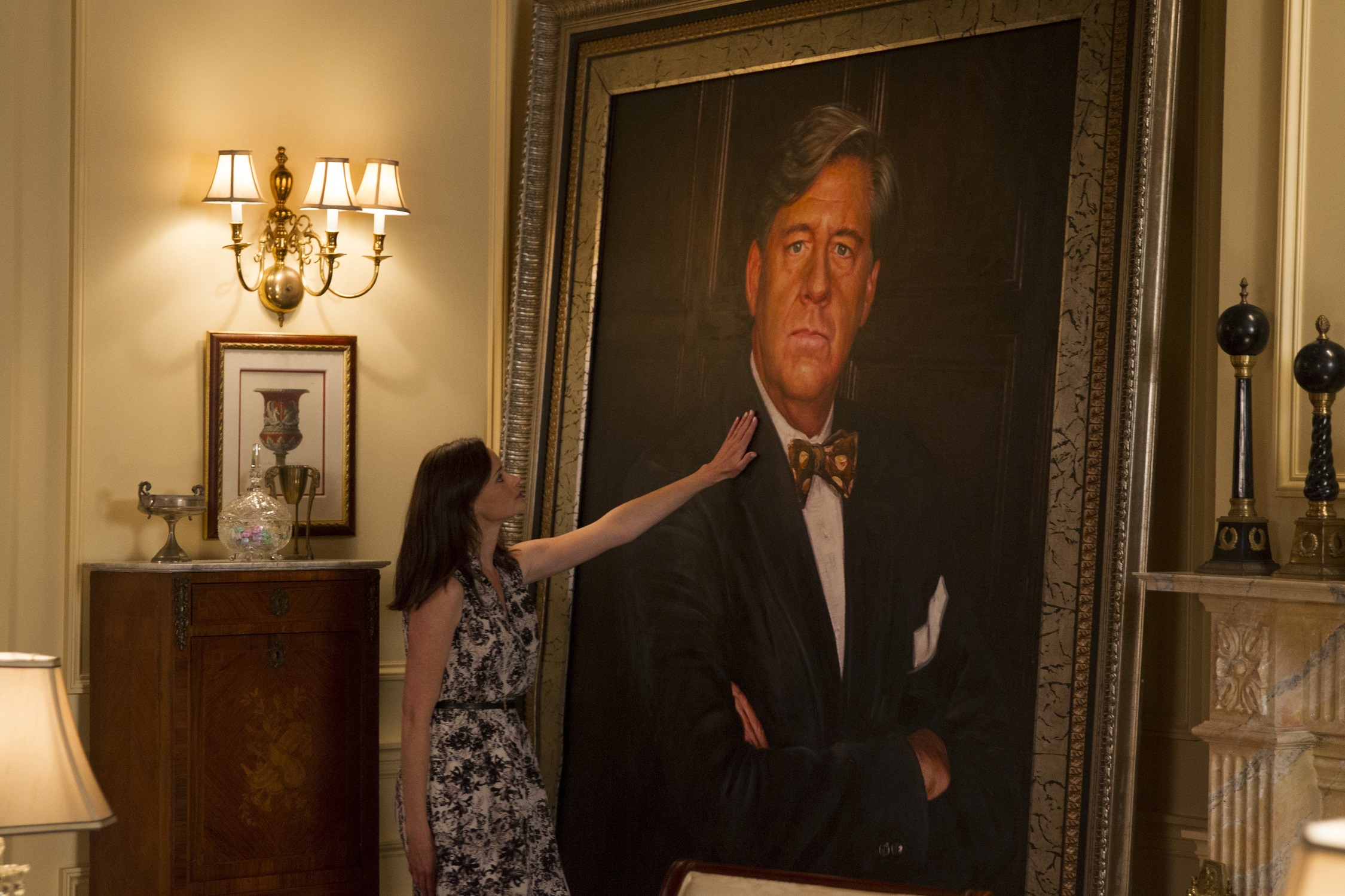 Alexis Bledel as Rory Gilmore stands next to a portrait of Ed Herman as Richard Gilmore in 'Gilmore GIrls: A Year in the LIfe'