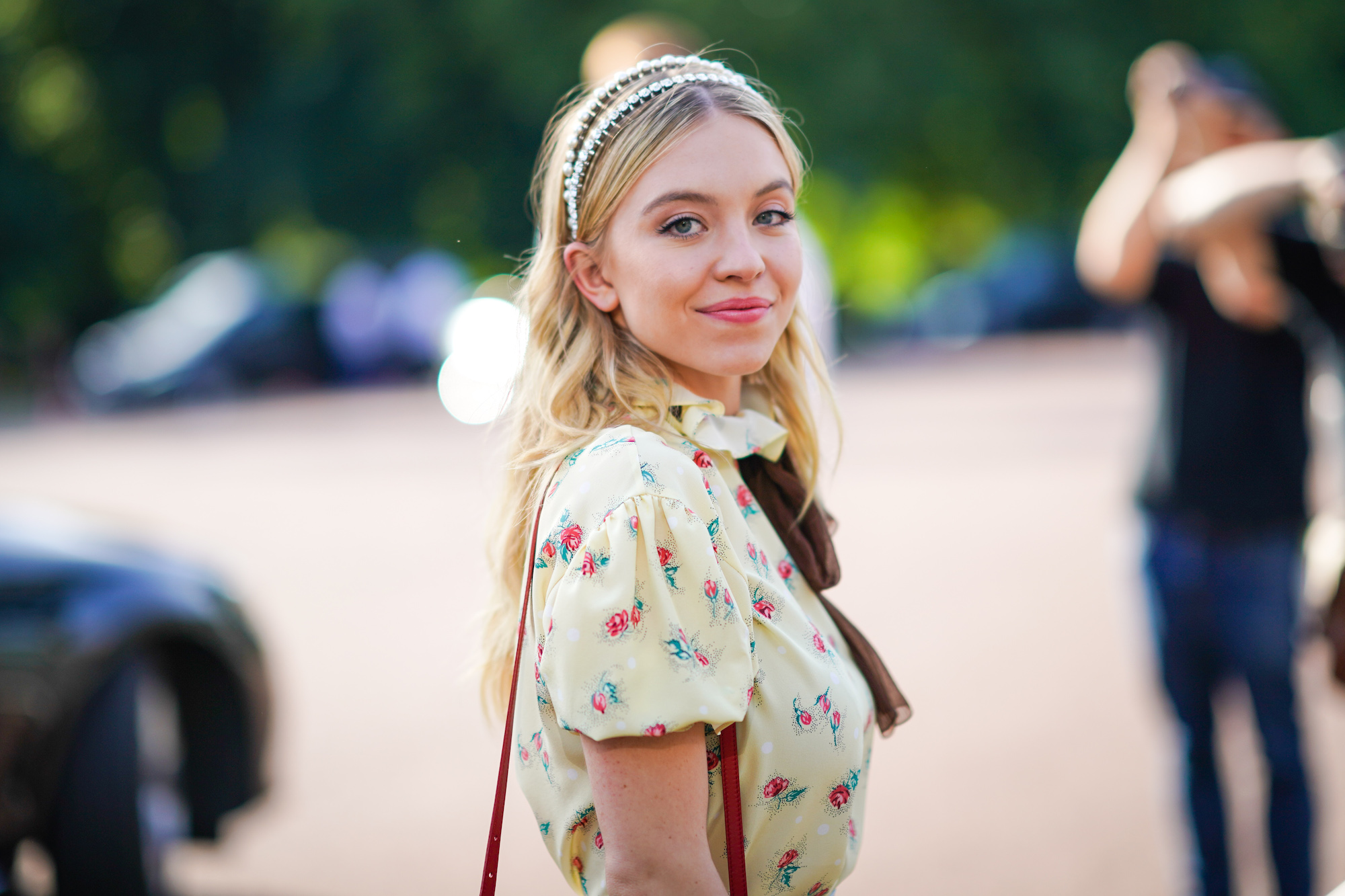 Sydney Sweeney smiling in front of a blurred background